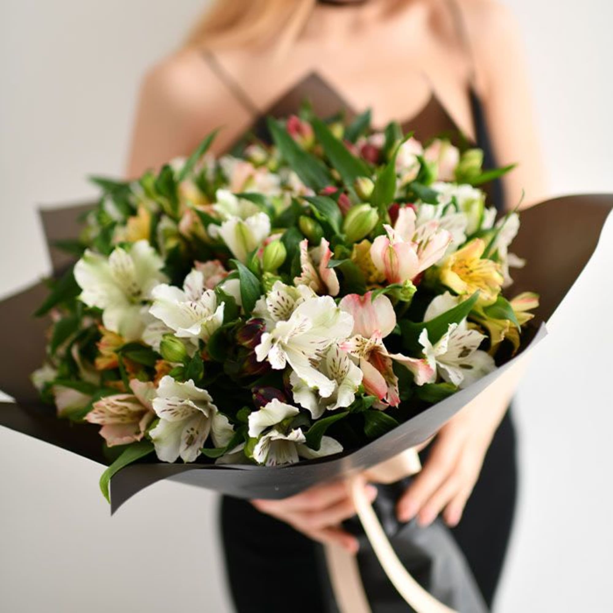Bouquet of white and pale pink alstroemeria wrapped in dark paper