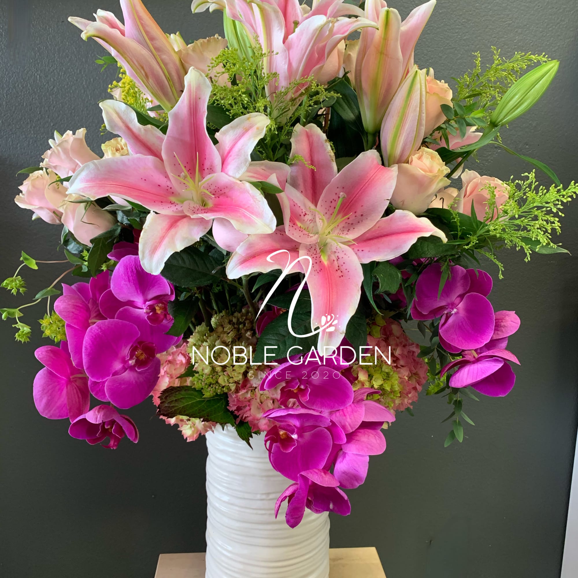 Pink lilies and magenta orchids in a white vase