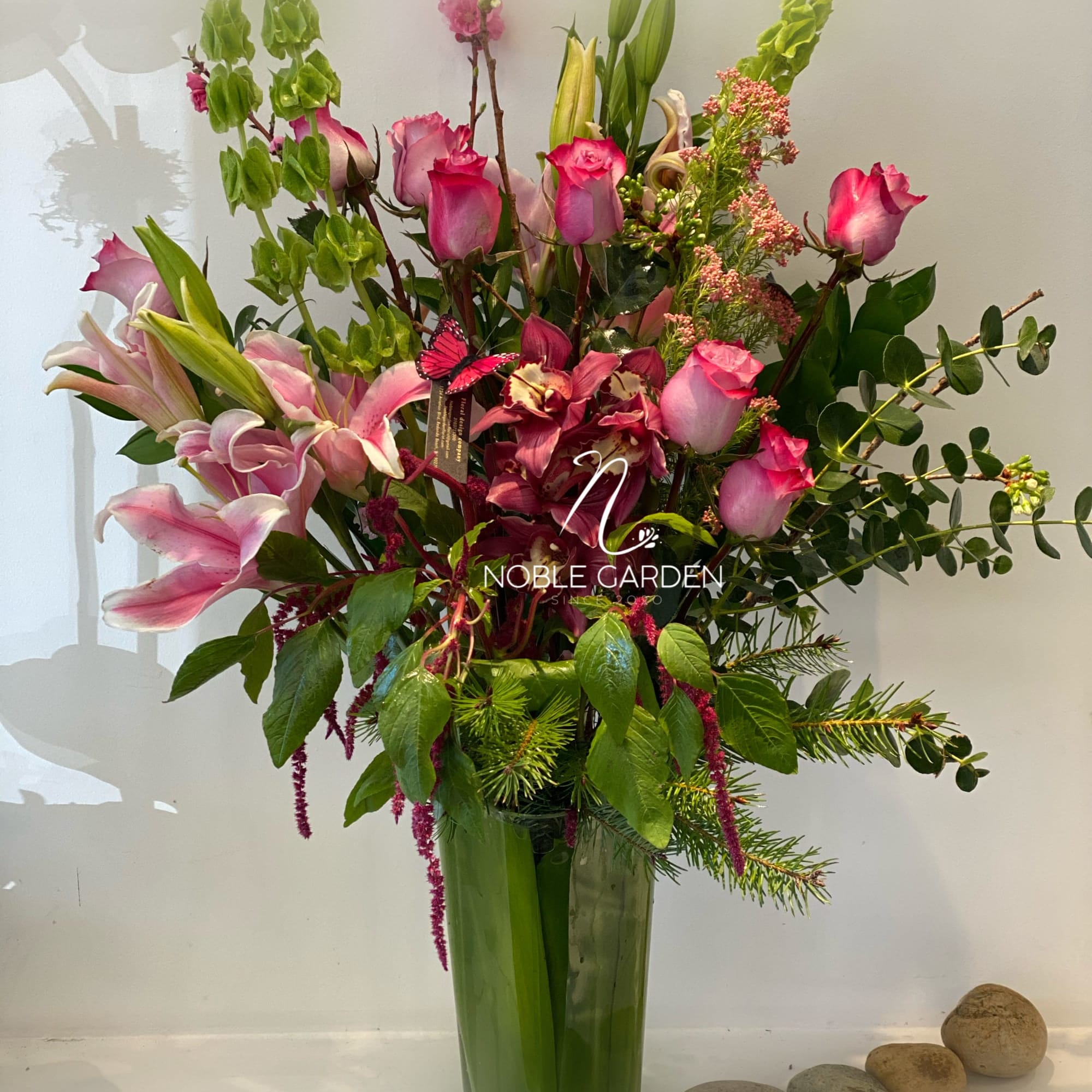 Tall mixed bouquet of pink roses and lilies in a glass vase