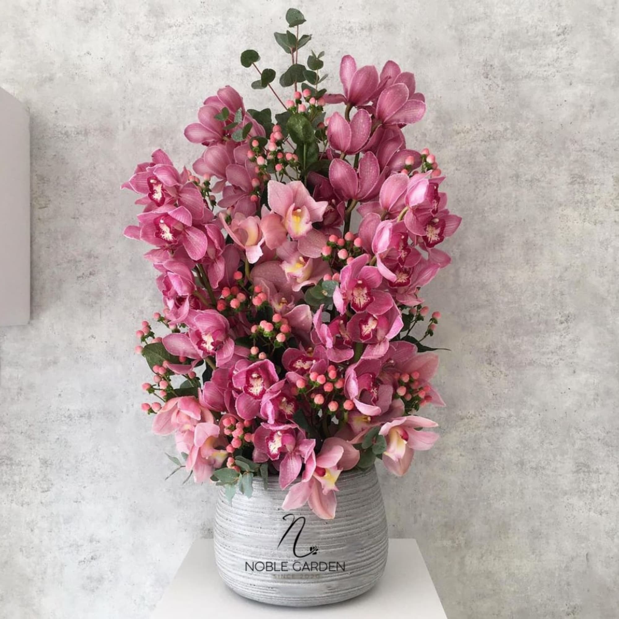 Pink orchid arrangement in a gray ceramic pot