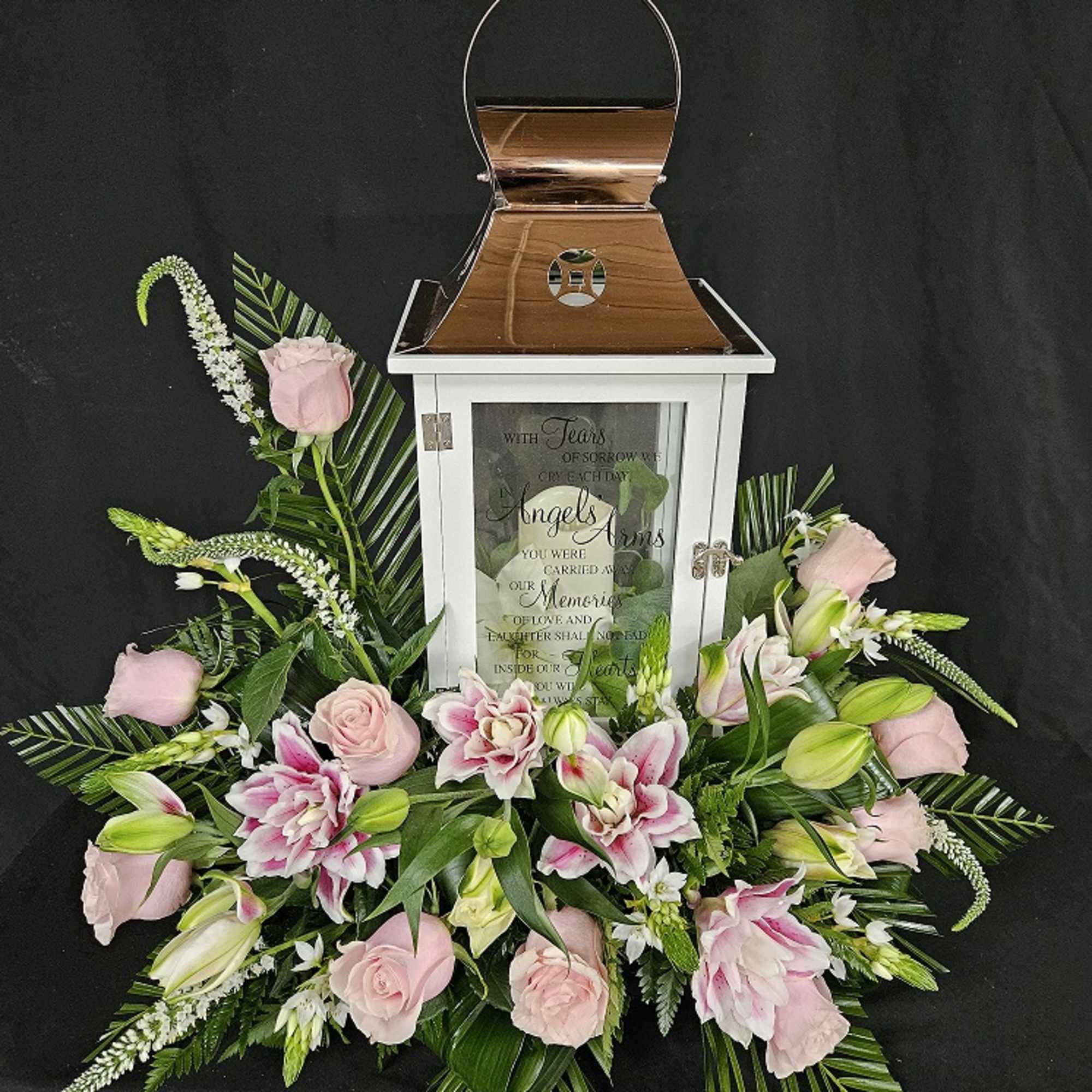 Pink roses and lilies arranged around a white memorial lantern