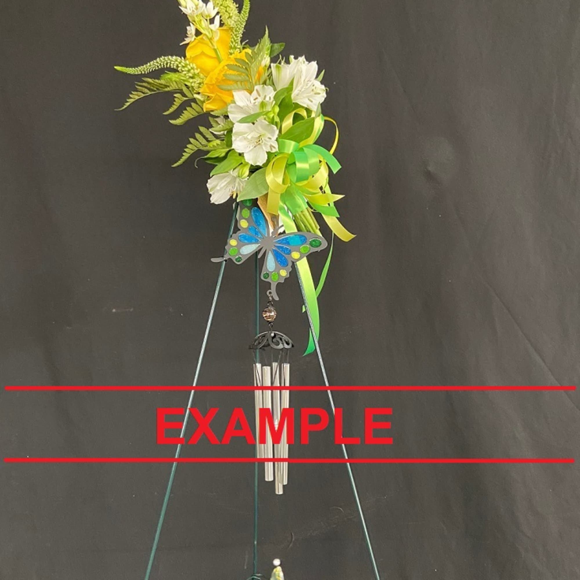 Yellow and white floral arrangement with a butterfly ornament and wind chimes