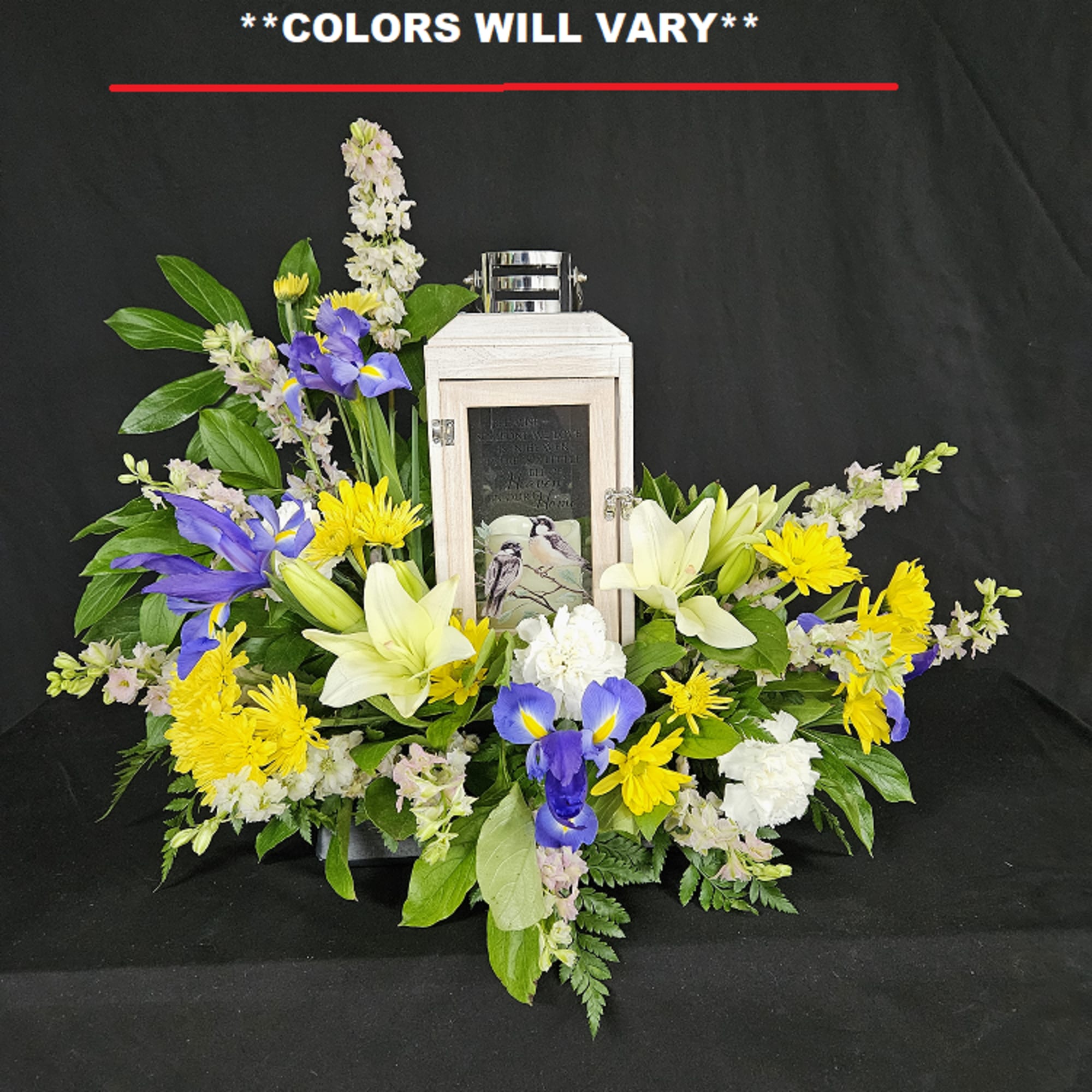 Floral funeral arrangement around a memorial lantern with white lilies and purple irises