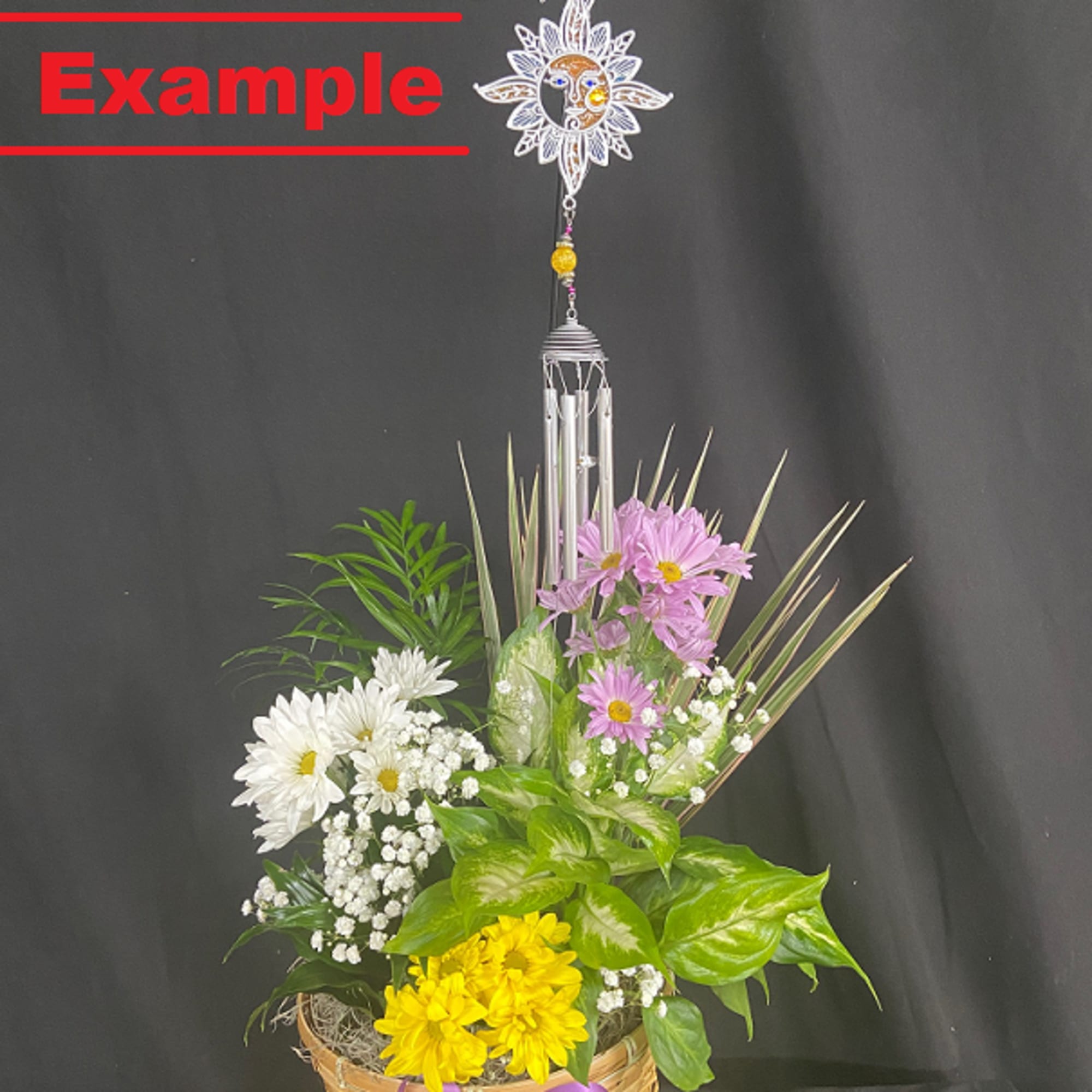 Basket arrangement of daisies and greenery with a hanging wind chime
