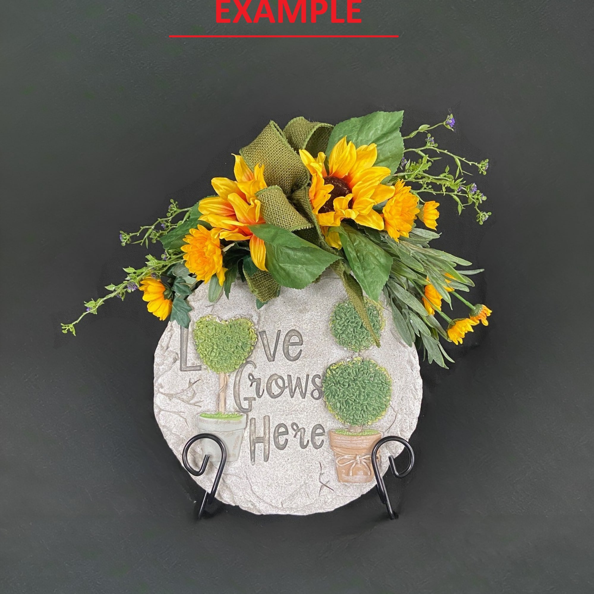 Sunflower arrangement on a decorative stone plaque with the words "Love Grows Here"