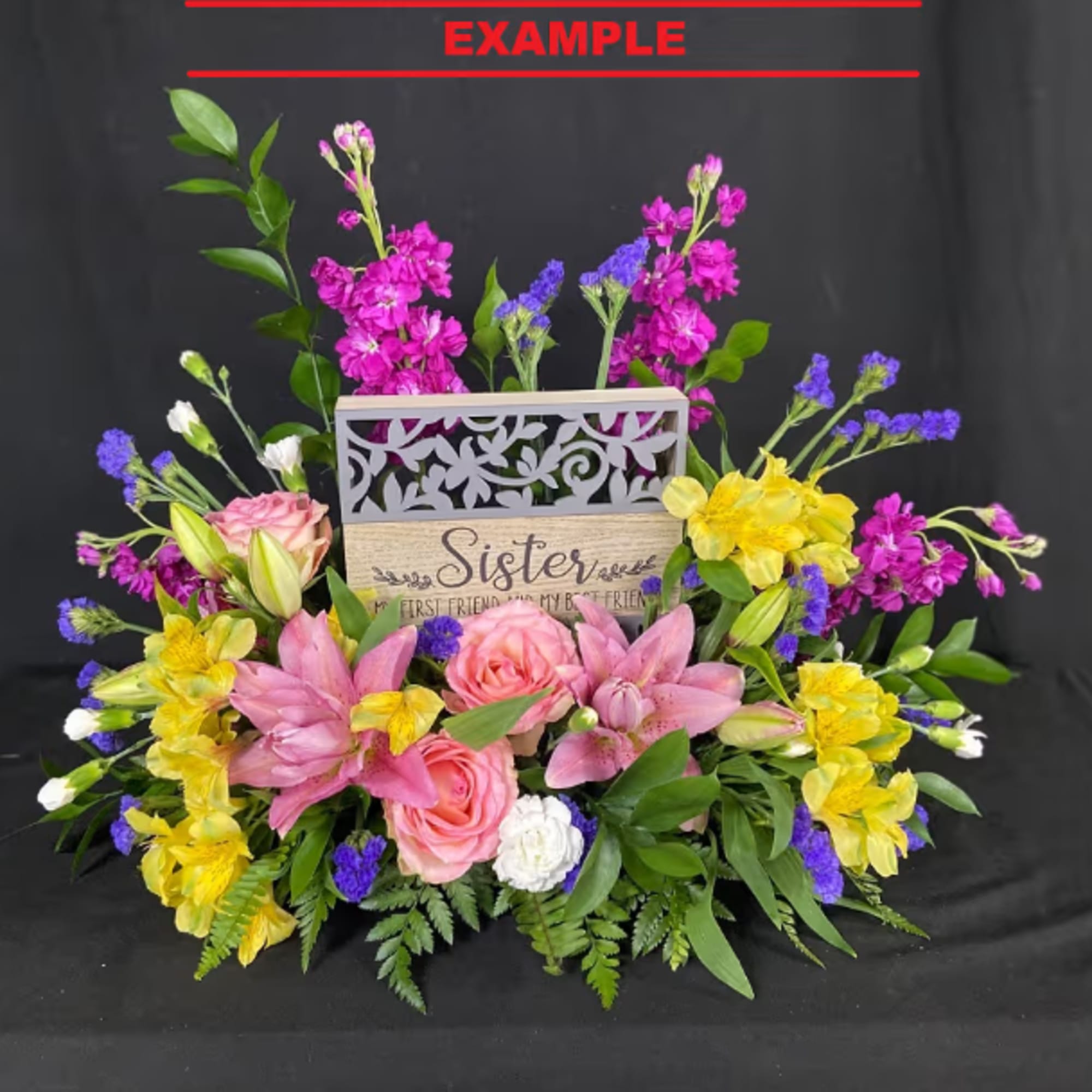 Mixed bouquet with pink roses, lilies, and yellow flowers around a decorative sign