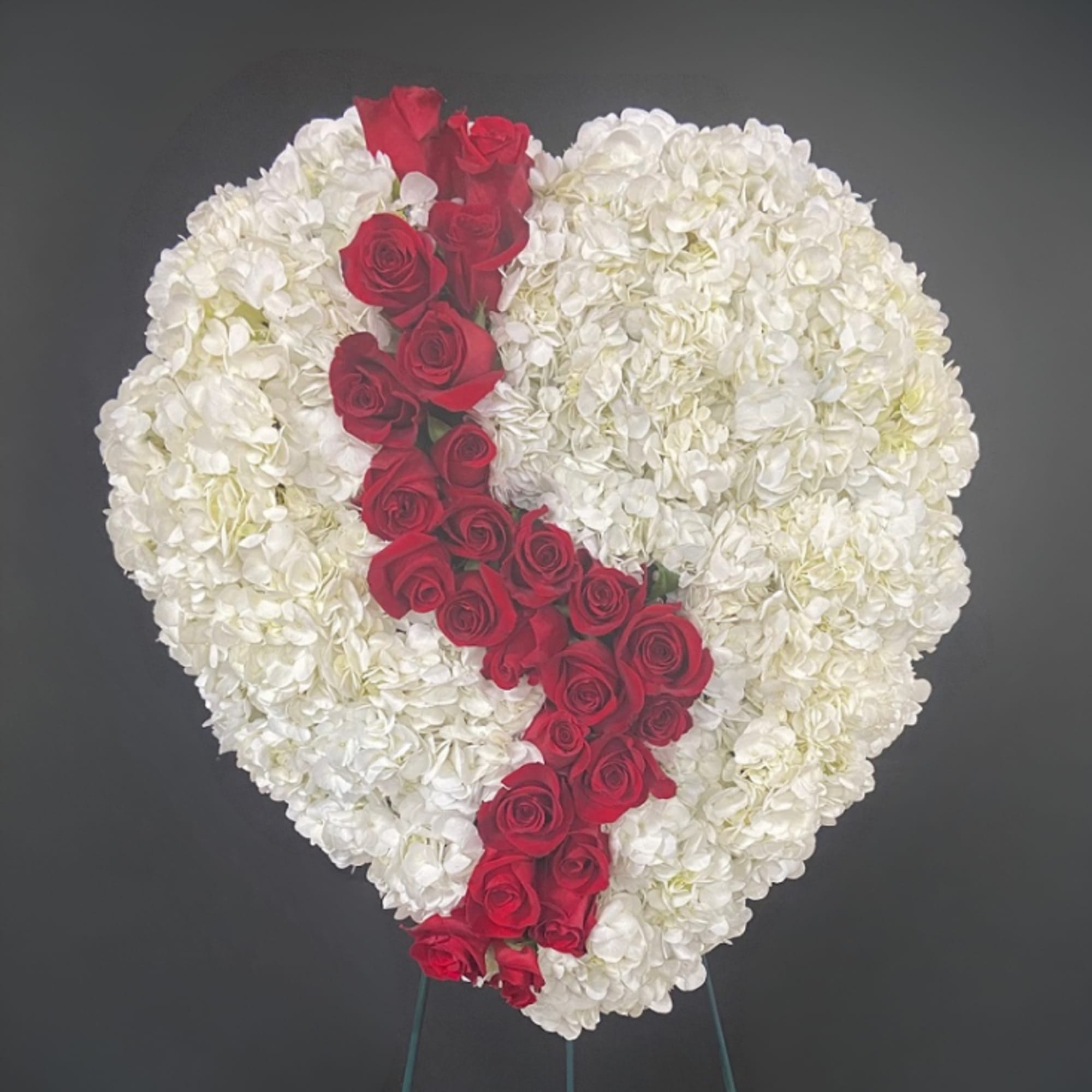 Heart-shaped white floral arrangement with a diagonal line of red roses