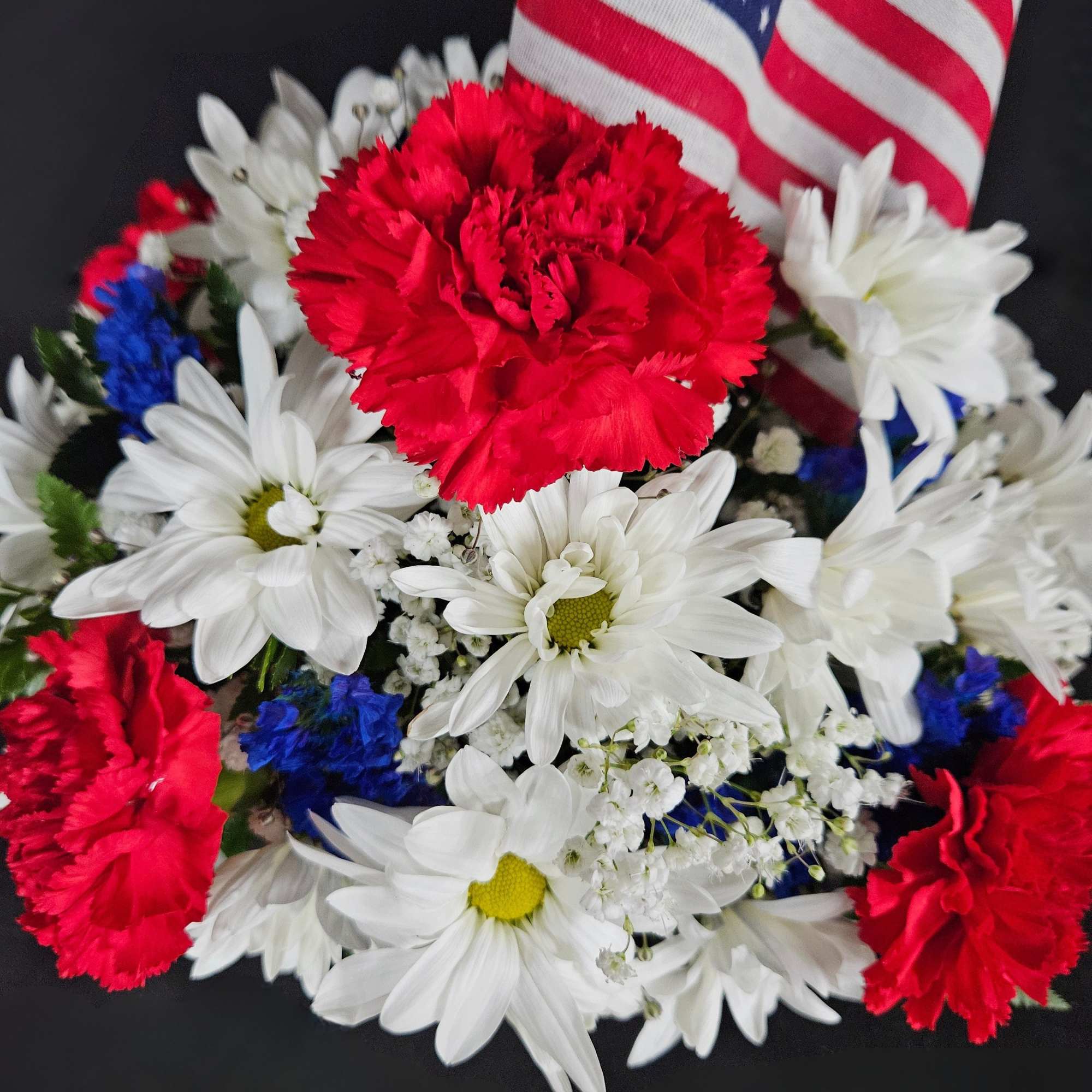 Red carnations and white daisies with an American flag