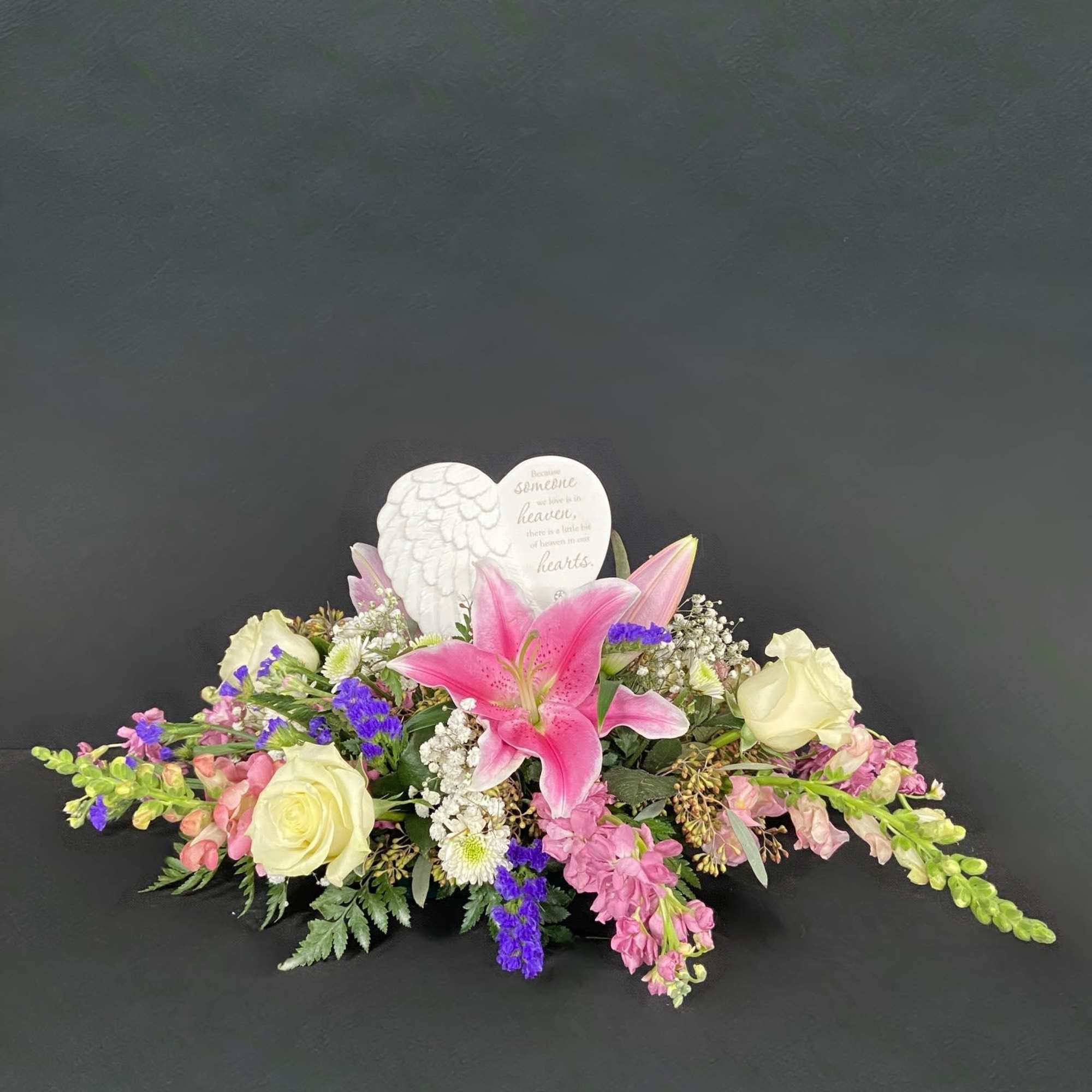 Sympathy floral arrangement with pink lilies and cream roses around a heart memorial plaque