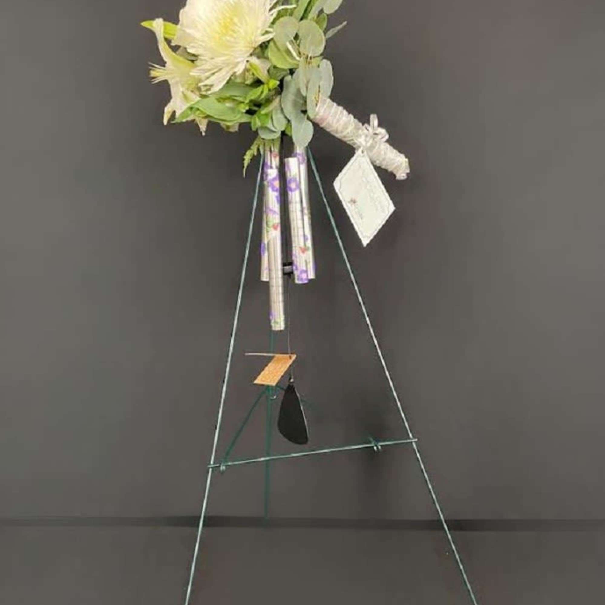 White floral spray on a standing easel with a hanging card