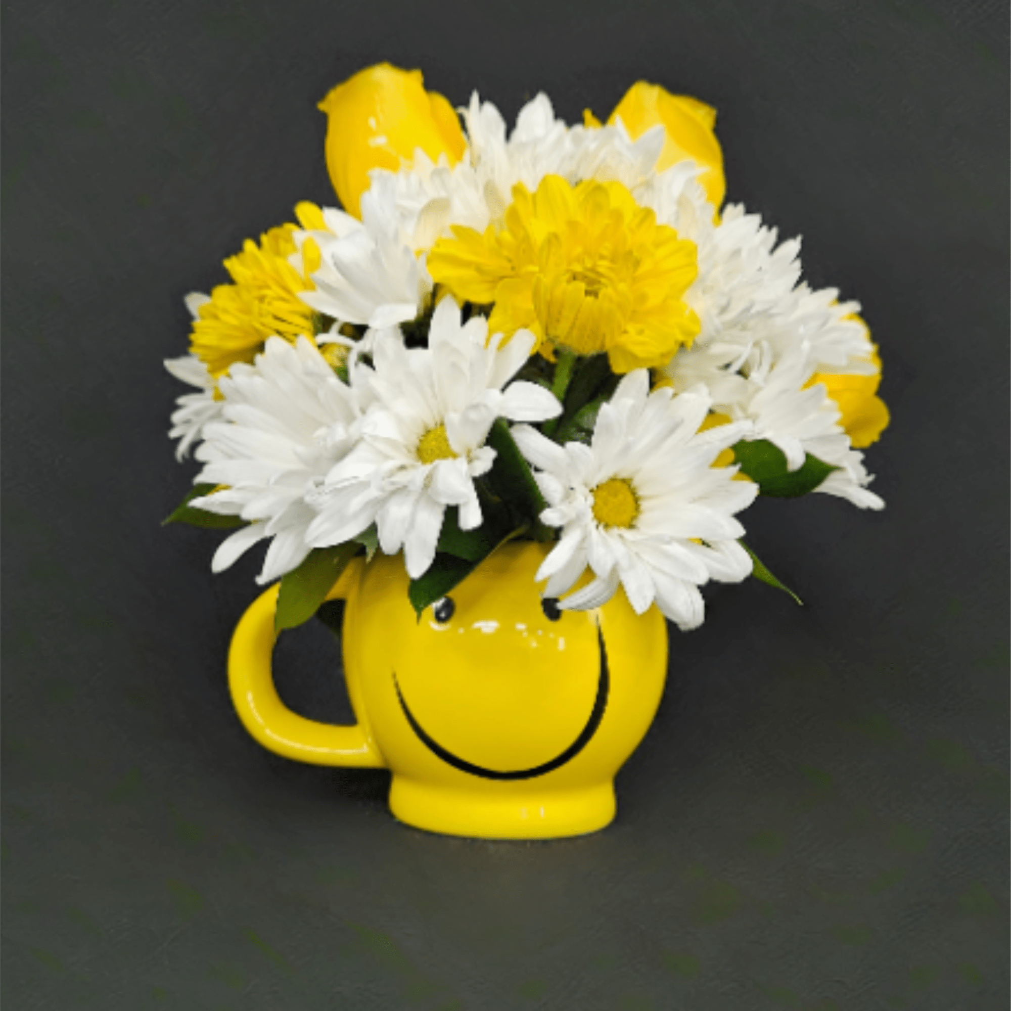 Yellow smiley-face mug filled with white daisies, yellow daisies, and yellow roses on a dark background