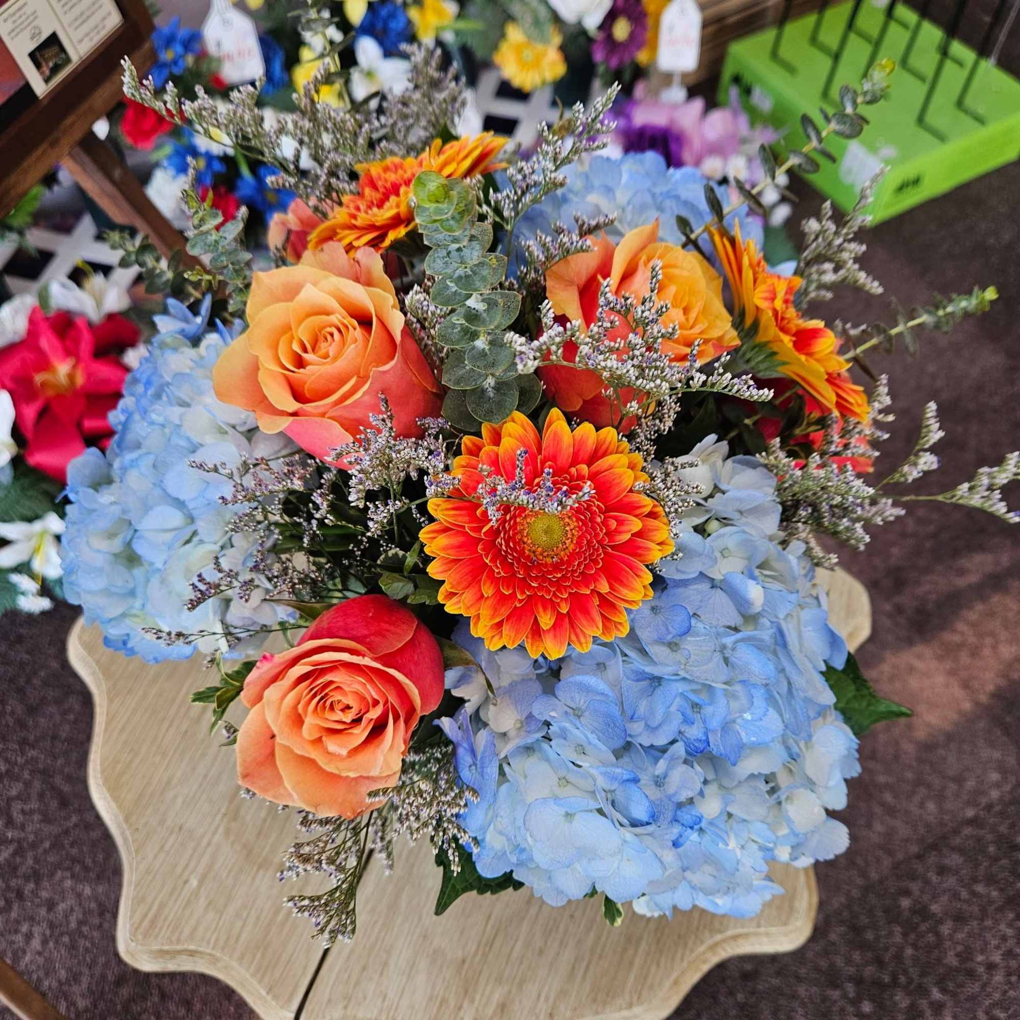 Lovely mix of blue hydrangea, cherry brandy roses and gerbera arranged in