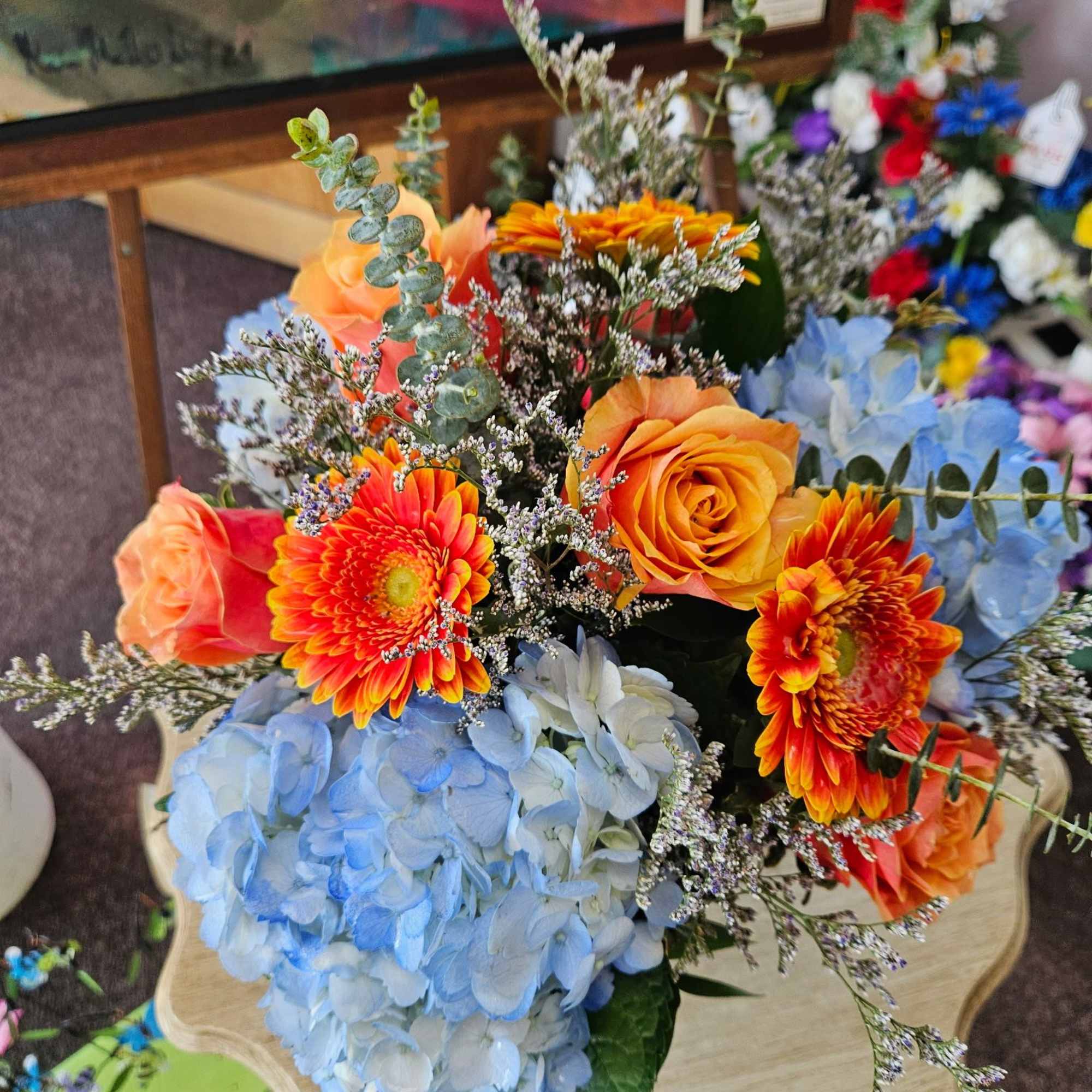 Lovely mix of blue hydrangea, cherry brandy roses and gerbera arranged in