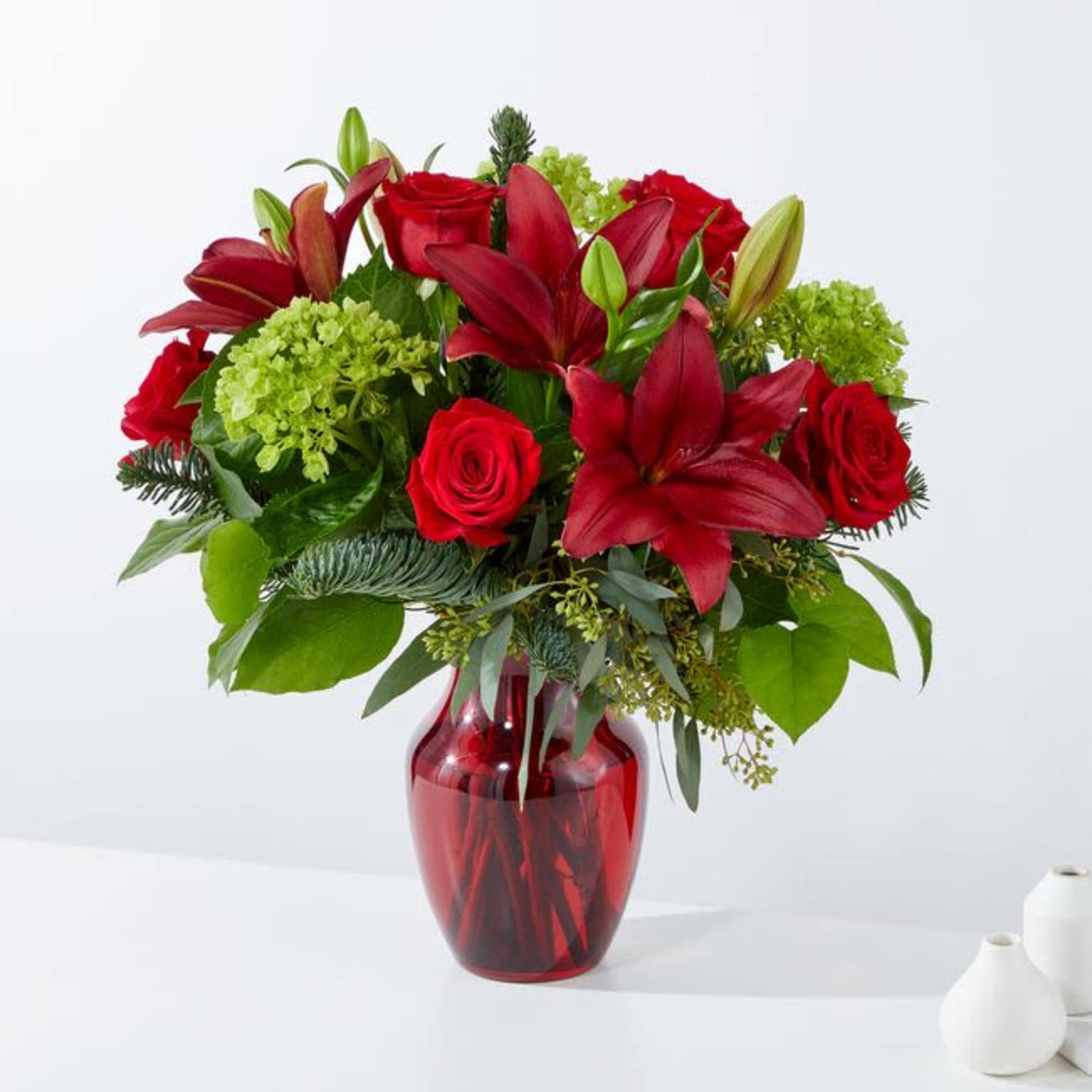 Red lilies and roses in a red glass vase