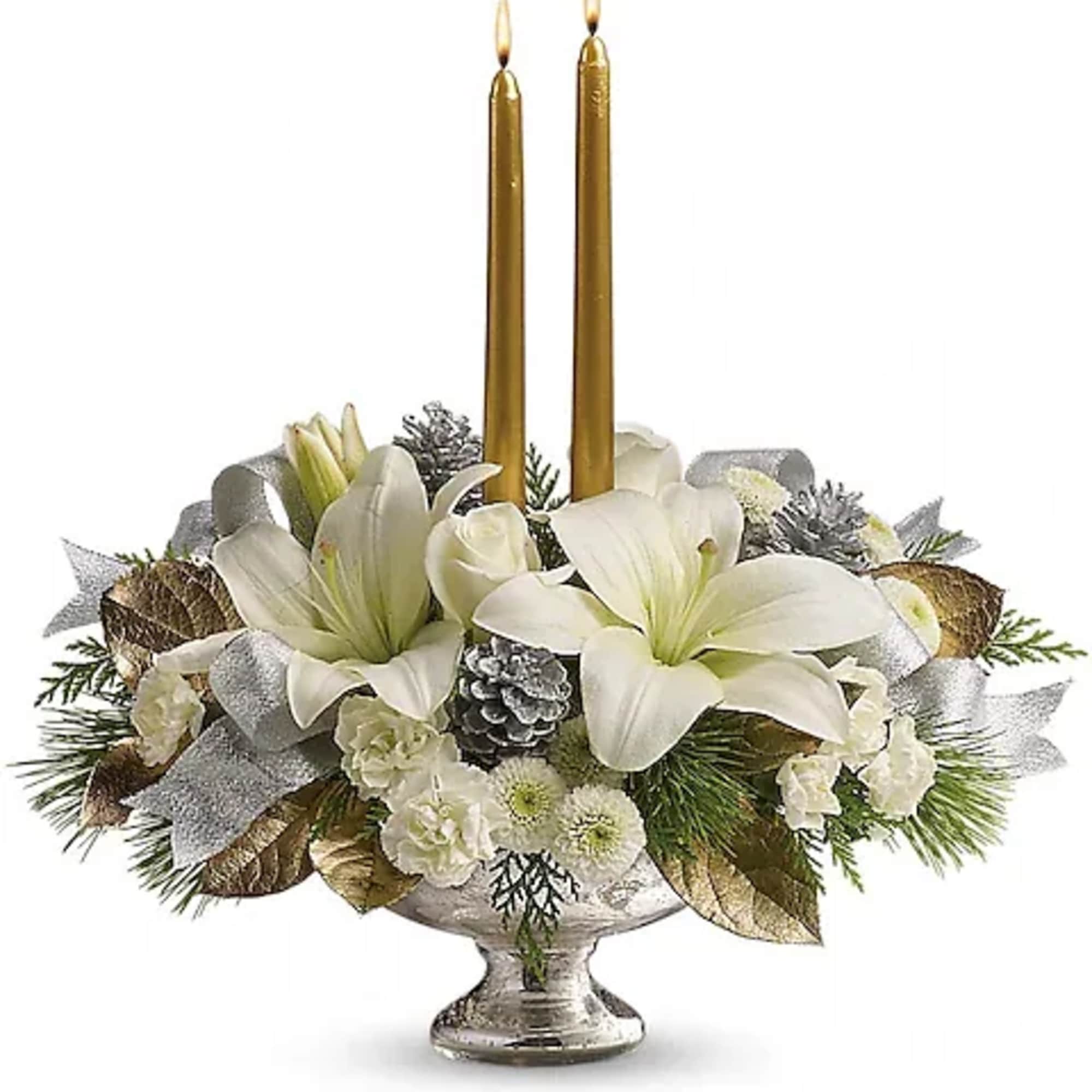 White floral centerpiece with two gold taper candles in a silver pedestal bowl