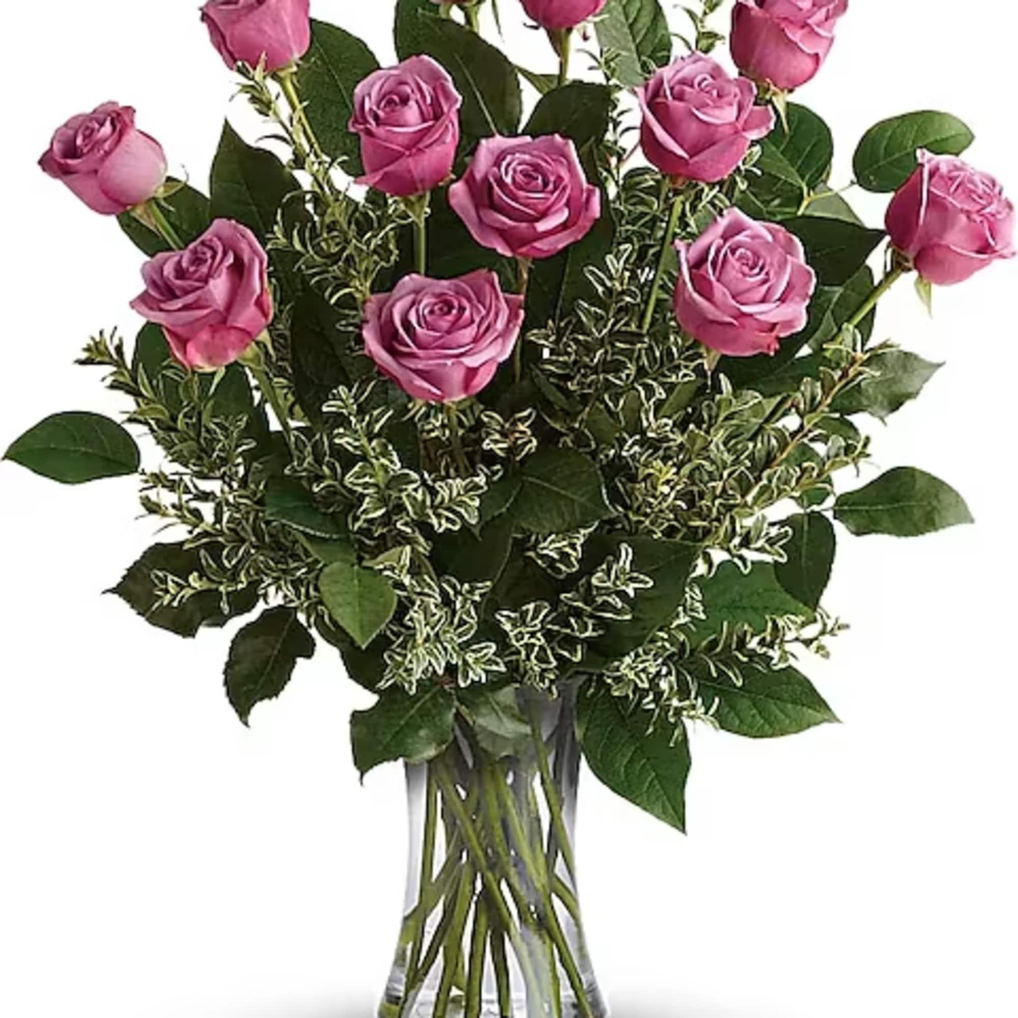 Pink roses arranged in a clear glass vase with greenery