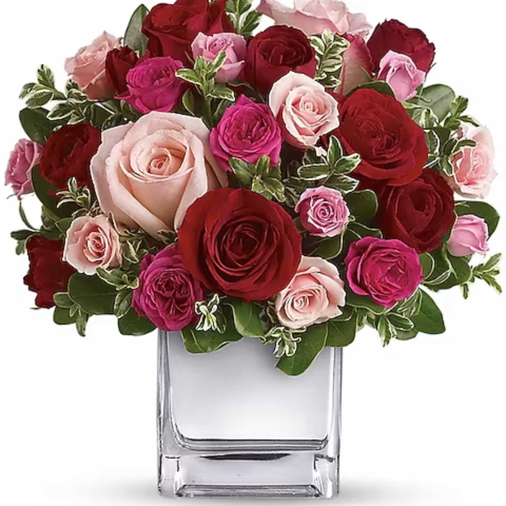 Bouquet of red, pink, and blush roses in a clear glass vase