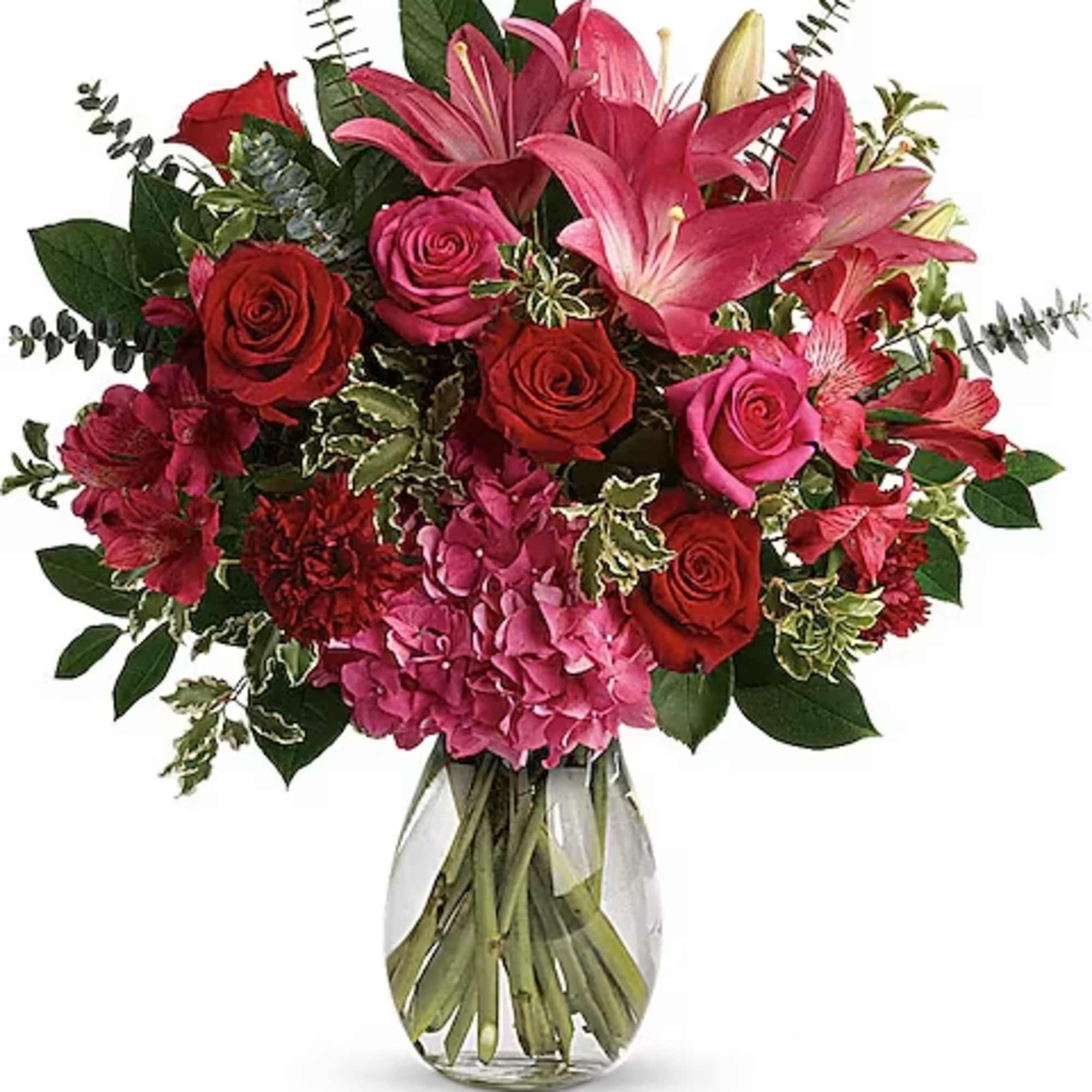 Bouquet of pink lilies, red roses, and hydrangea in a glass vase