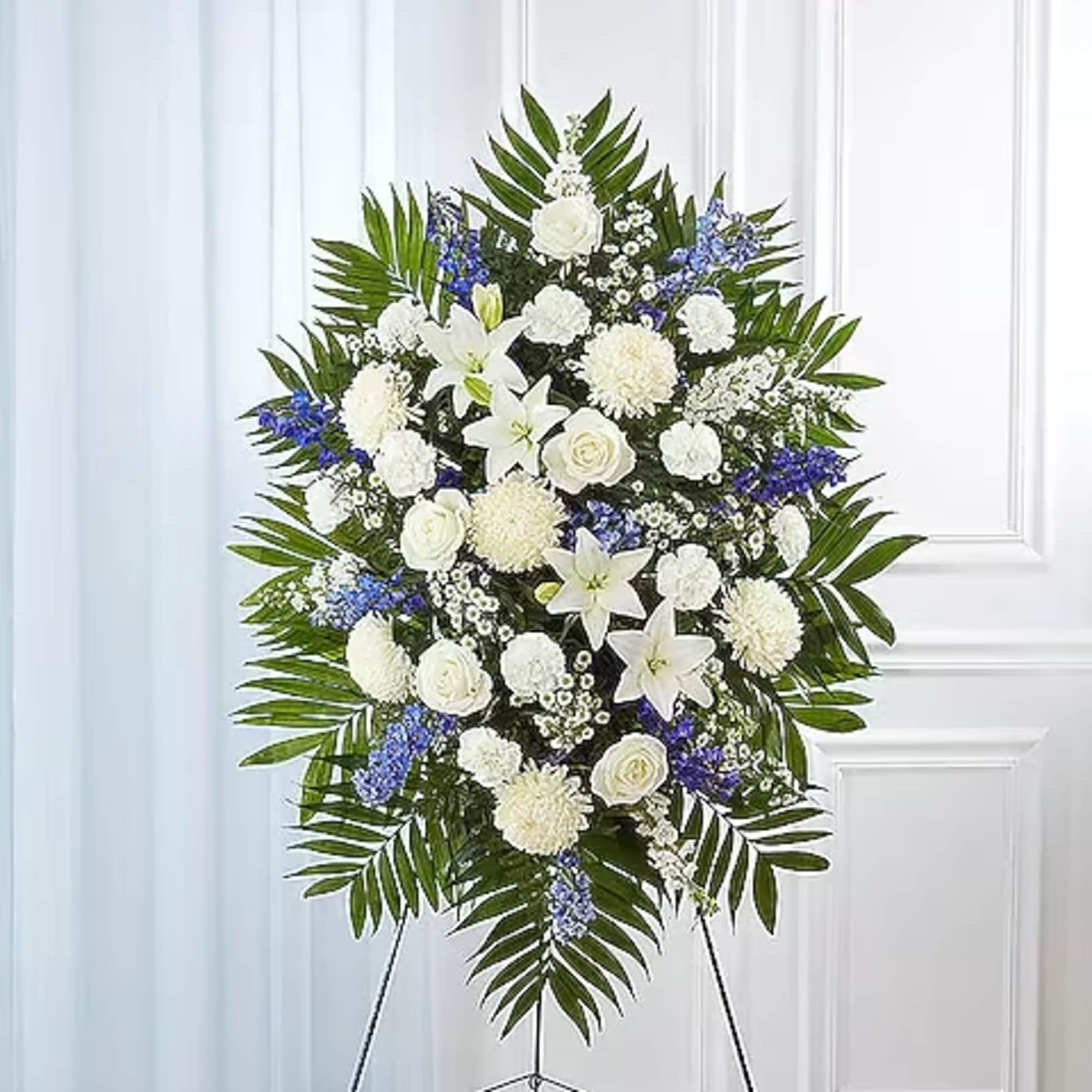 Standing funeral spray of white and blue flowers on an easel