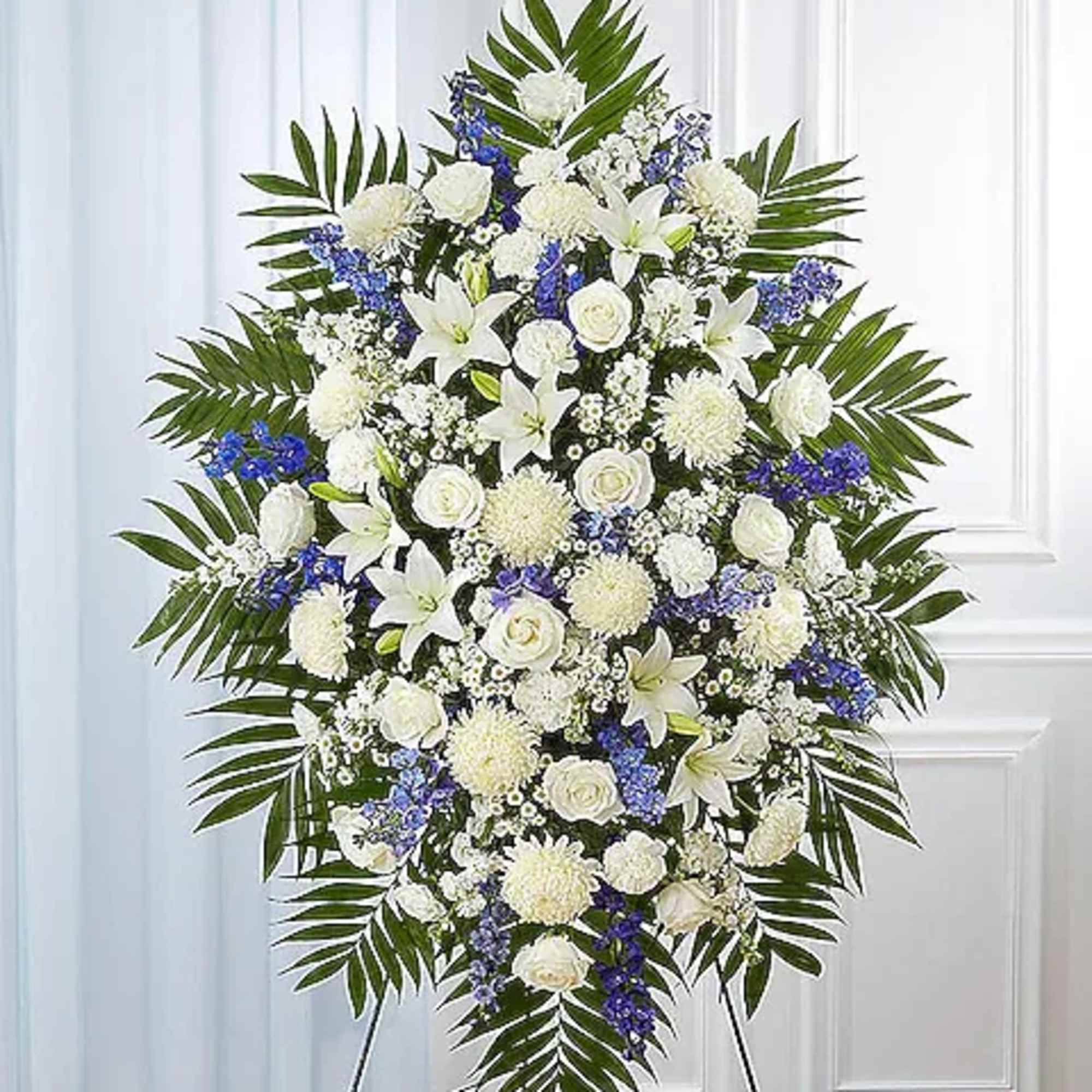 Large white and blue funeral spray on an easel