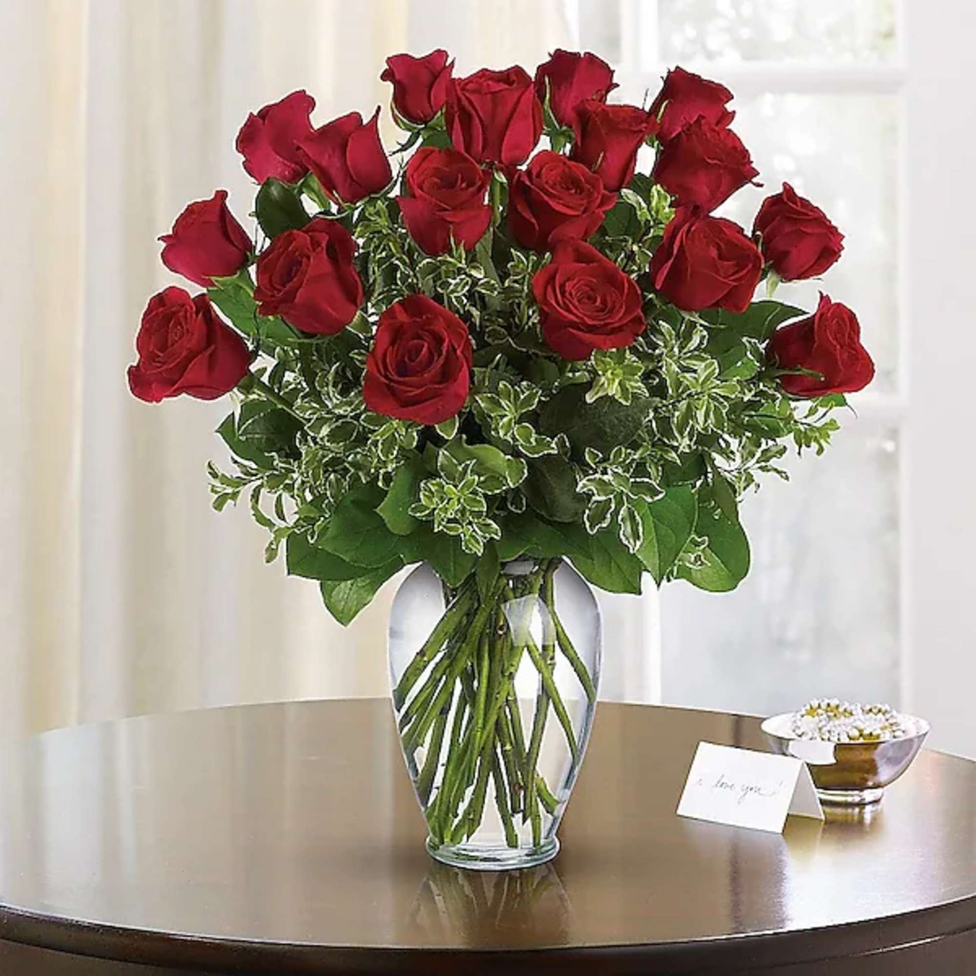 Red roses arranged in a clear glass vase on a table