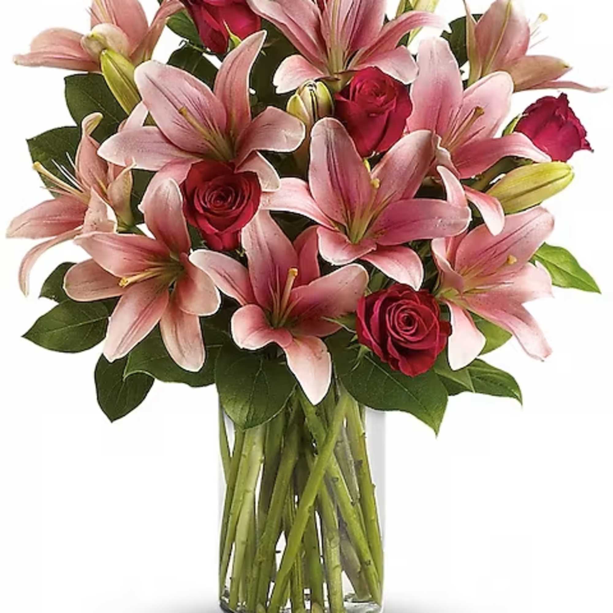 Pink lilies and red roses arranged in a clear glass vase