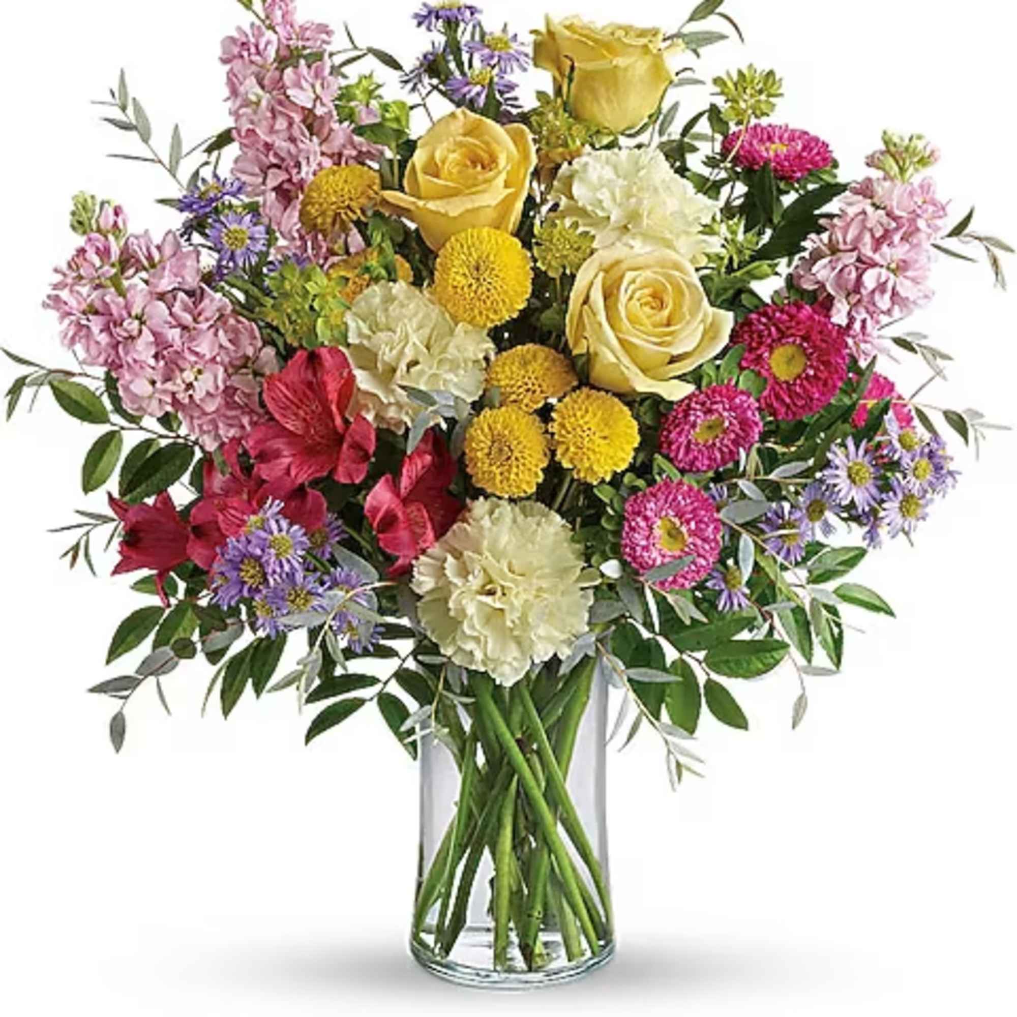 Mixed bouquet of yellow roses, pink flowers, and purple daisies in a glass vase