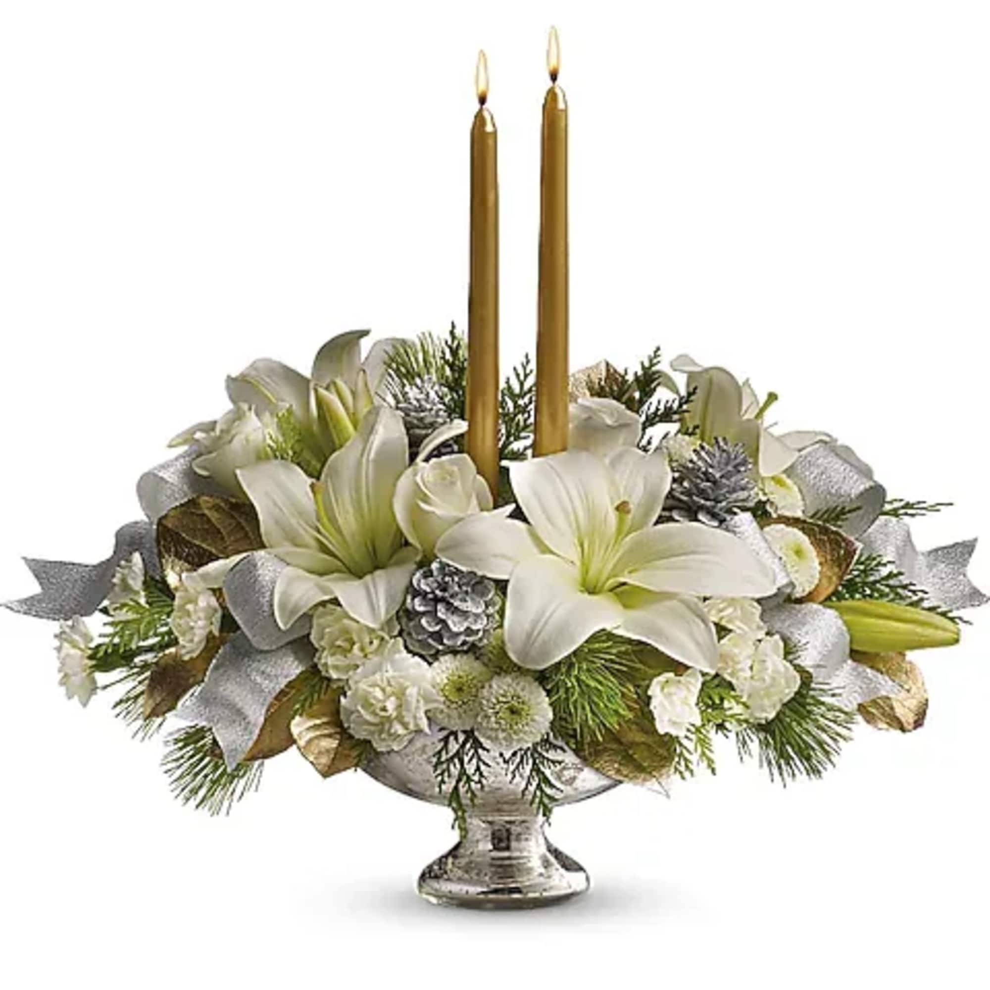 White floral centerpiece with two gold taper candles in a silver vase