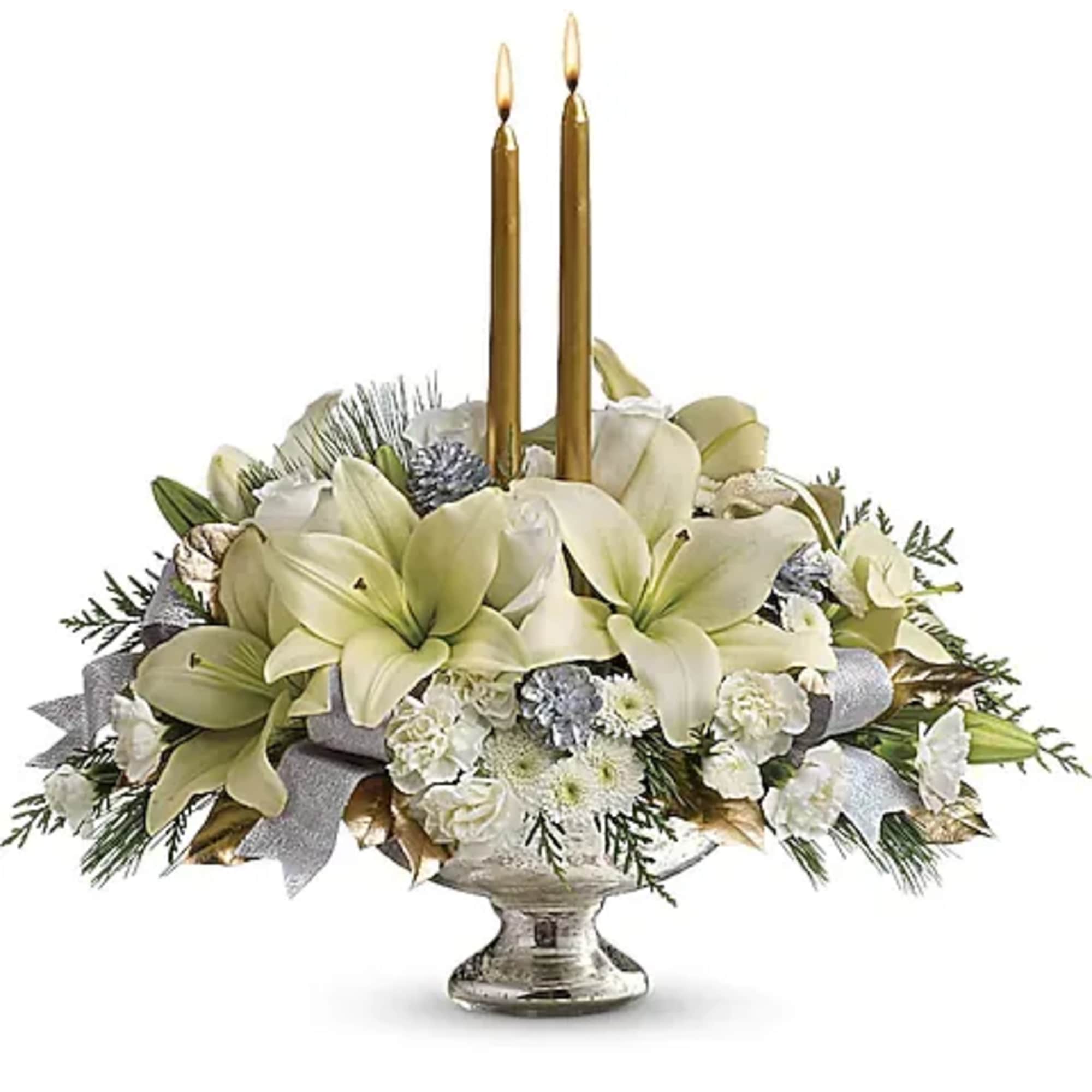 White floral centerpiece with two gold taper candles in a silver pedestal bowl
