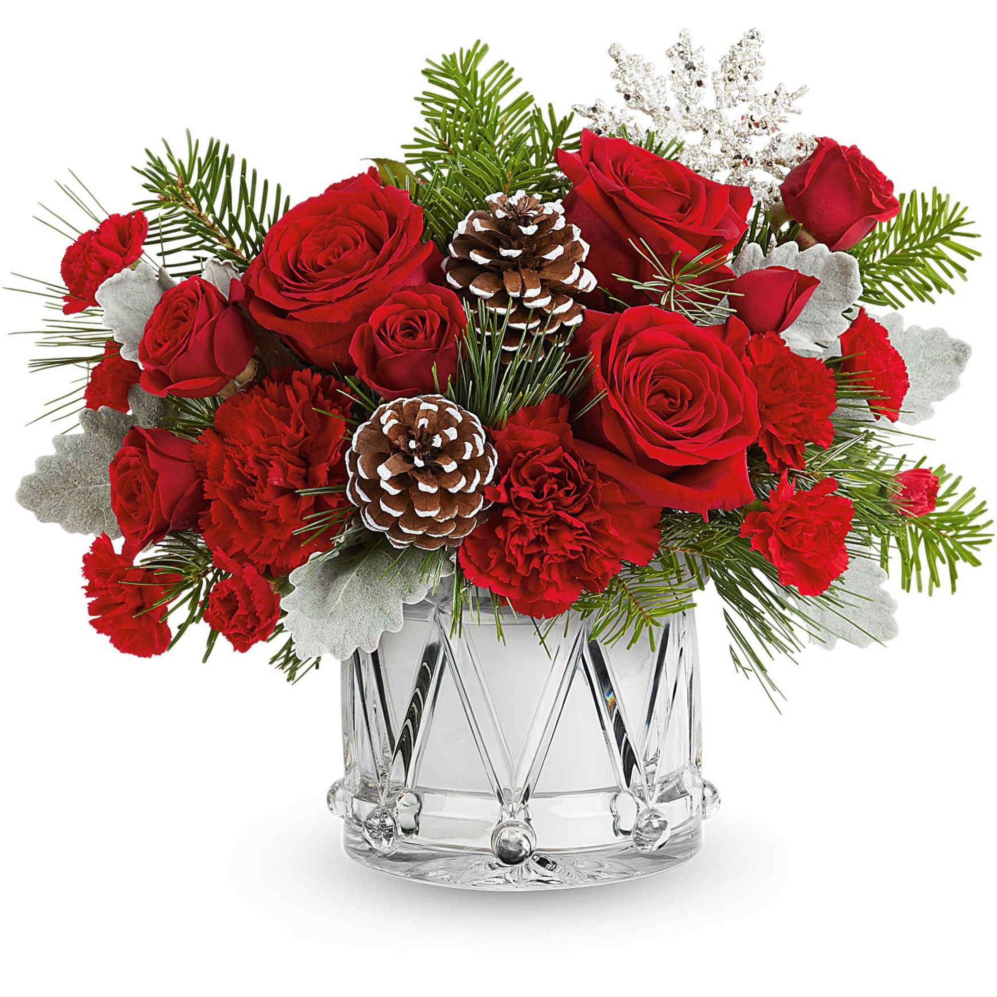 Red roses and carnations in a clear glass vase with pinecones and winter greenery