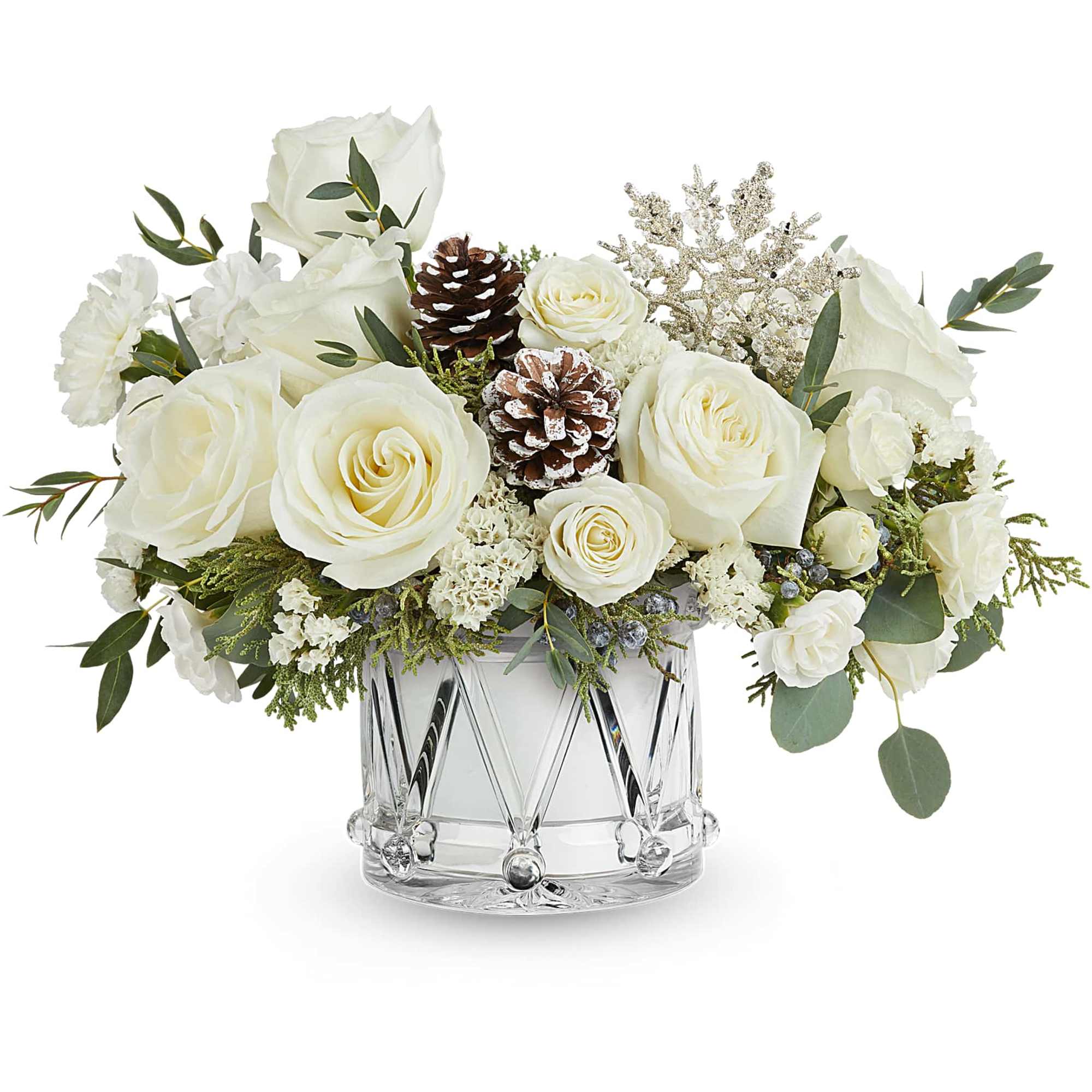 White roses arranged in a clear glass vase with pinecones and greenery