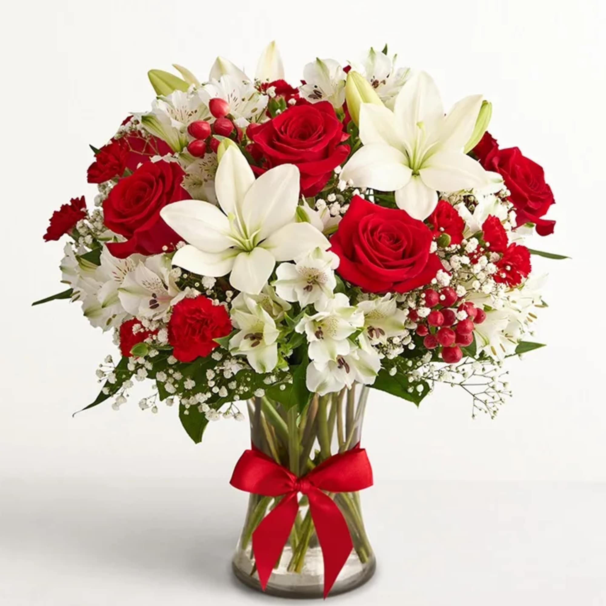Red roses and white lilies in a glass vase with a red ribbon