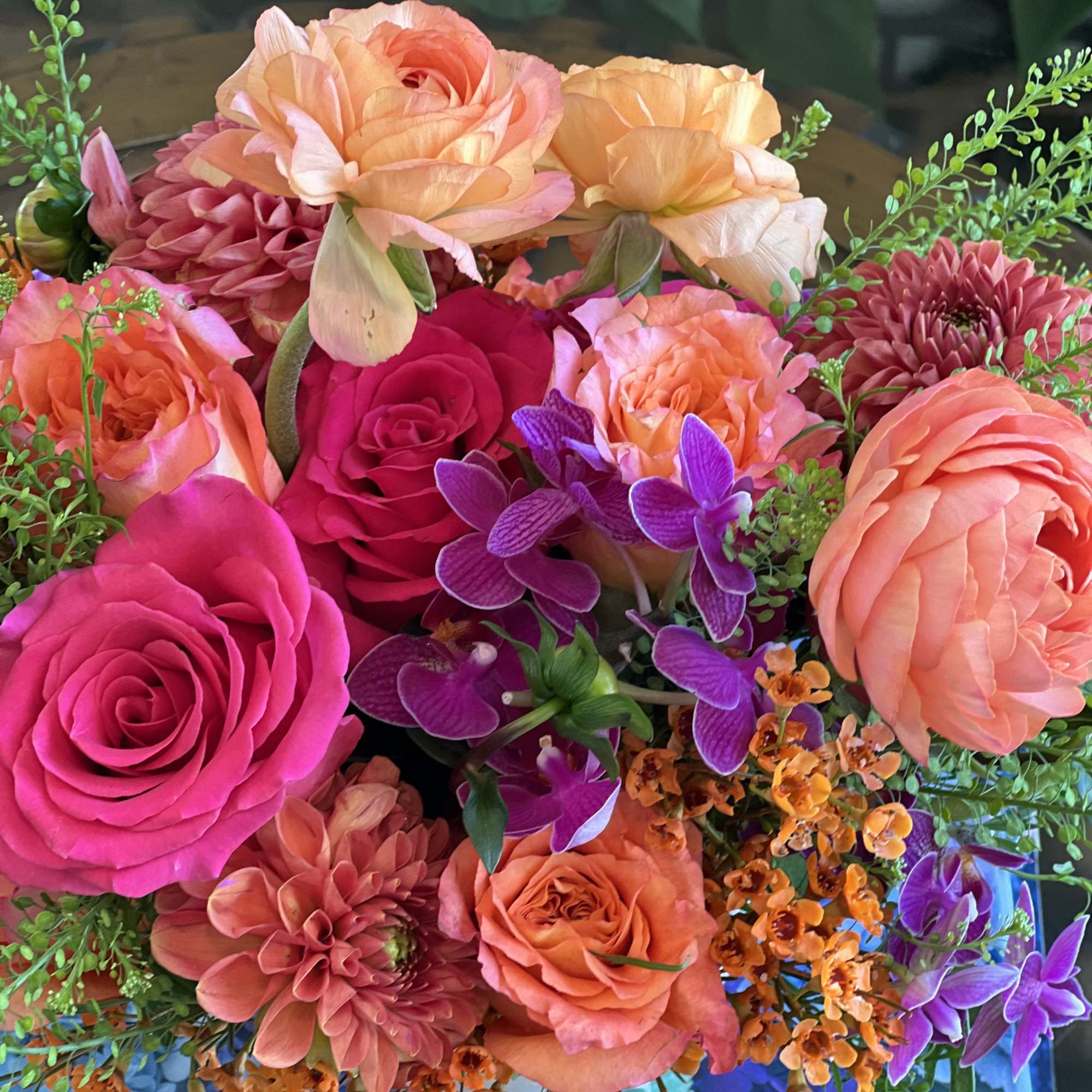 Bright bouquet of pink and peach roses with purple orchids and small orange flowers