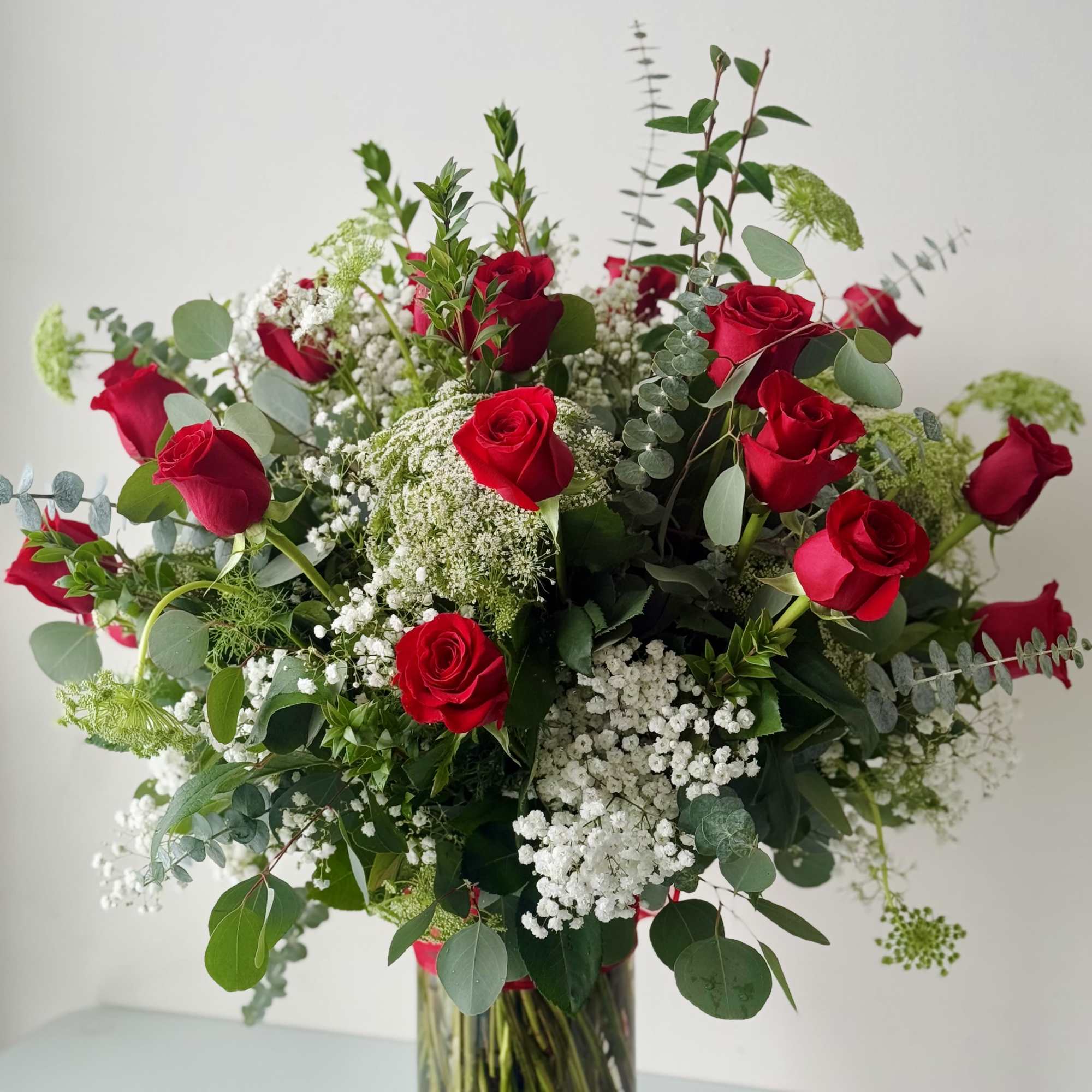 Bouquet of red roses and white filler flowers in a clear glass vase