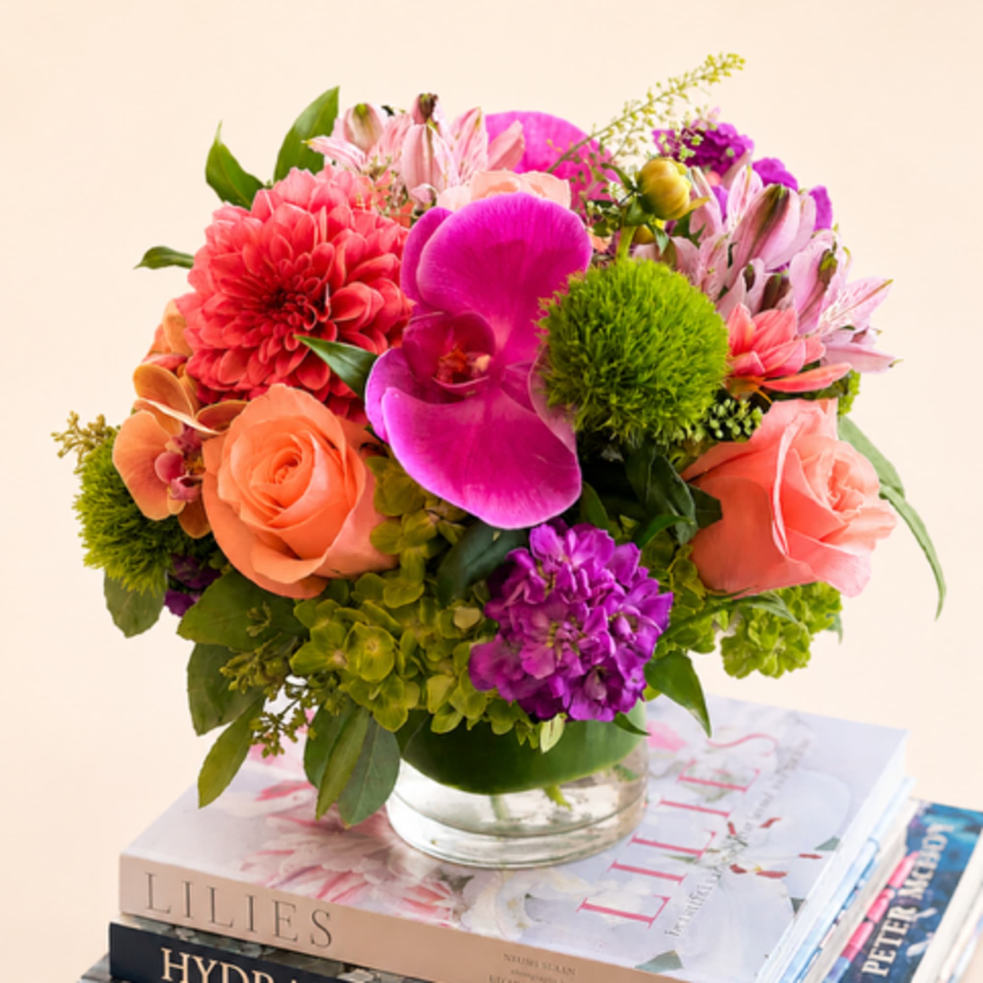 Mixed bouquet of pink, coral, and purple flowers in a glass vase