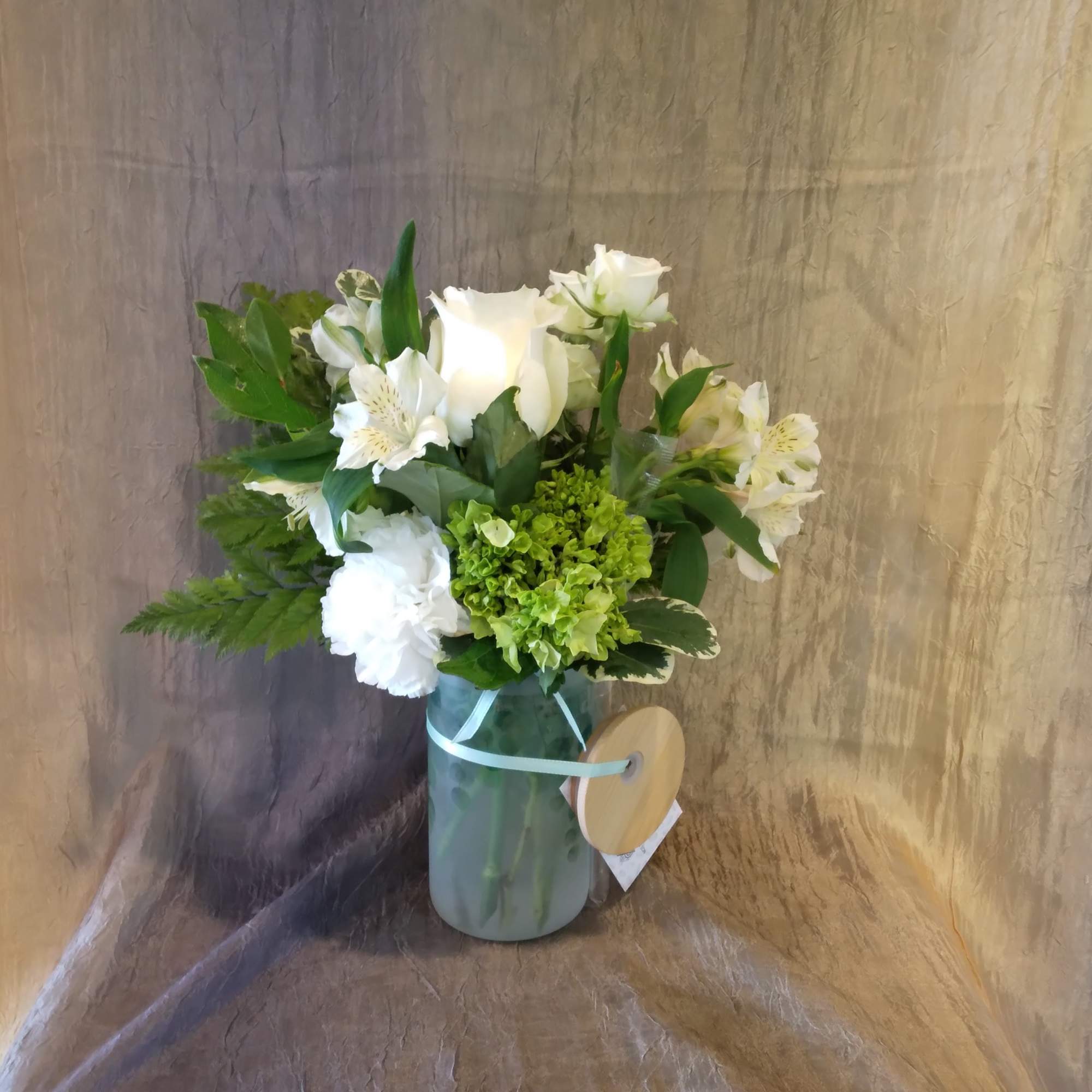 White roses and alstroemeria in a glass vase with green hydrangea
