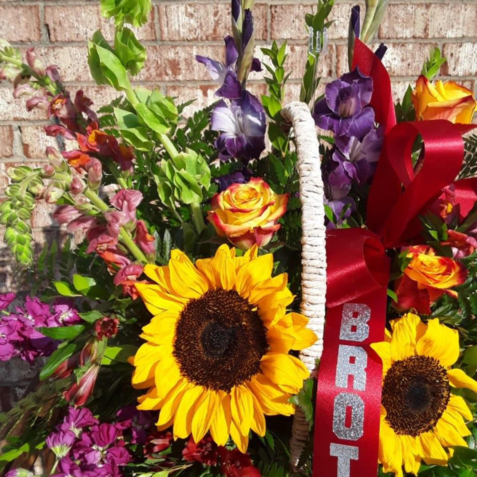 Basket of mixed flowers with sunflowers and a red ribbon