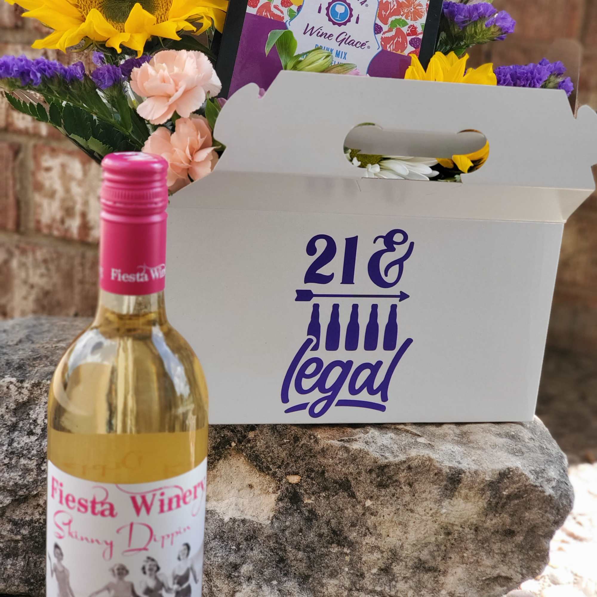 Gift box with flowers and a wine bottle in front