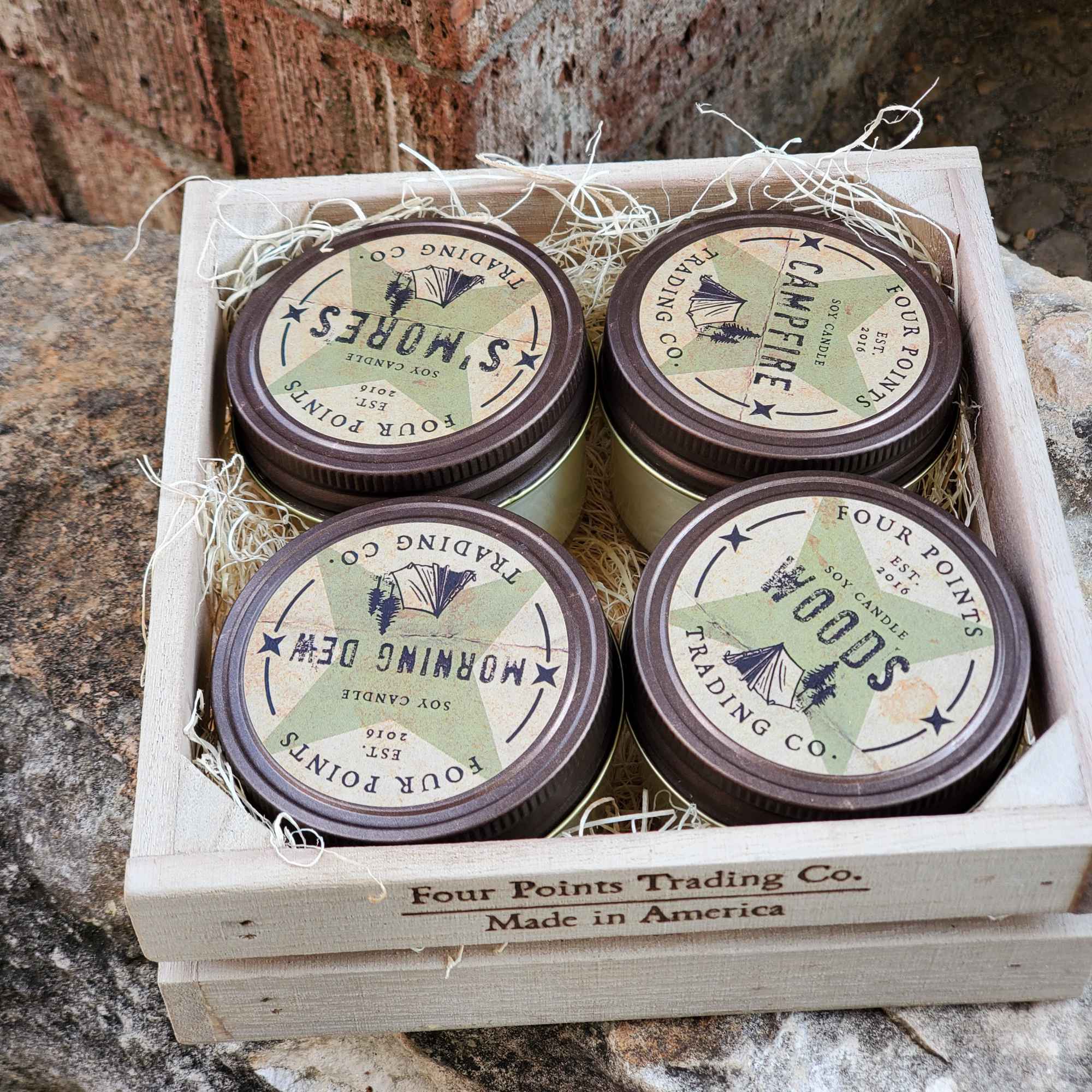 Four scented candles in a wooden crate with shredded paper filler
