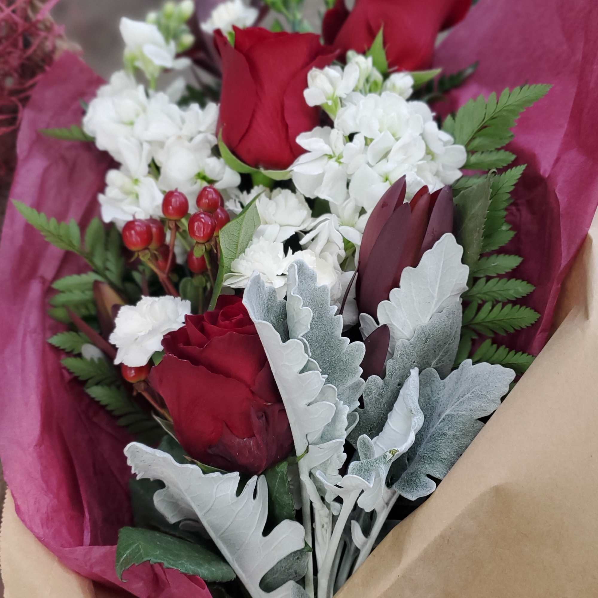 Bouquet of red roses and white flowers wrapped in pink paper