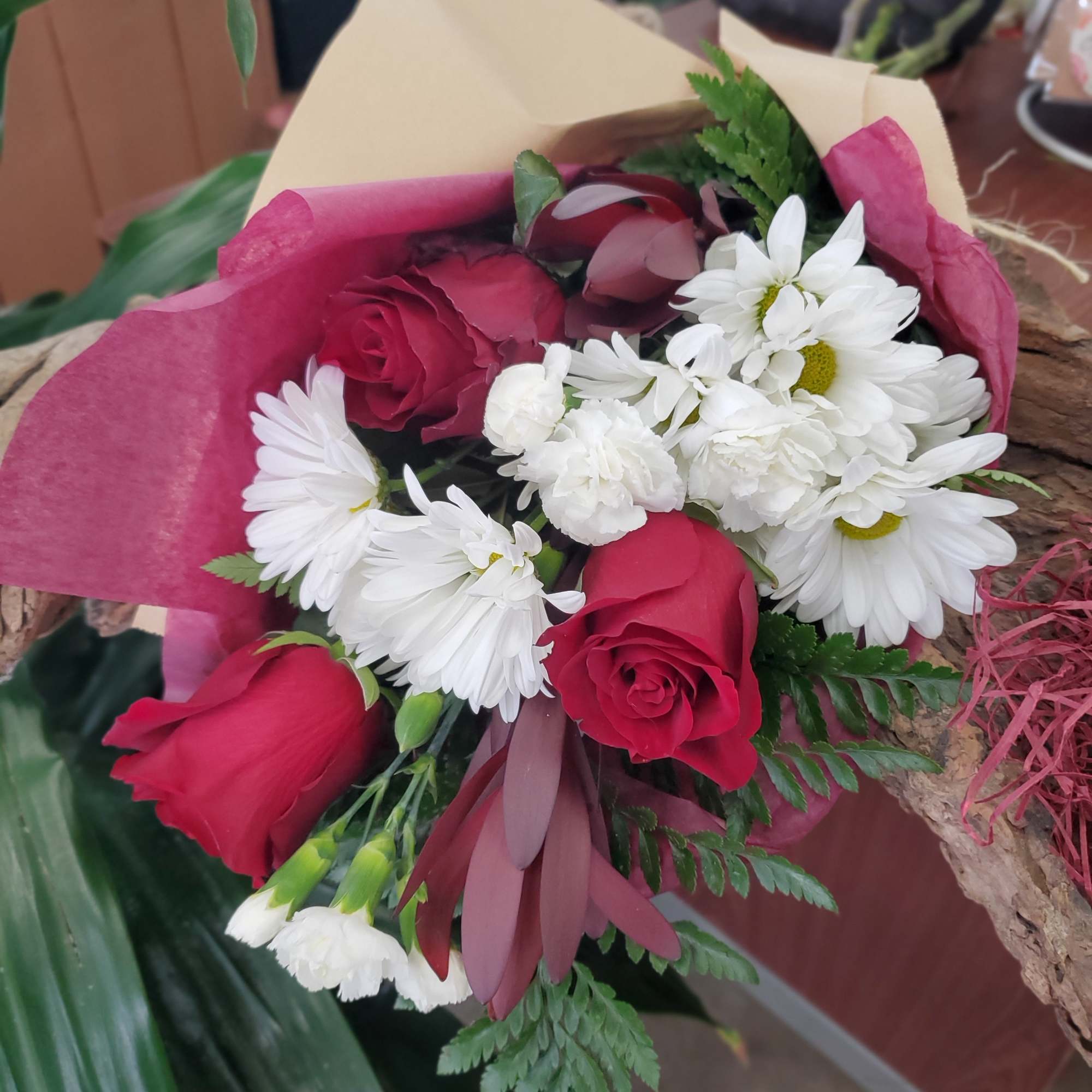 Bouquet of red roses and white daisies wrapped in pink paper