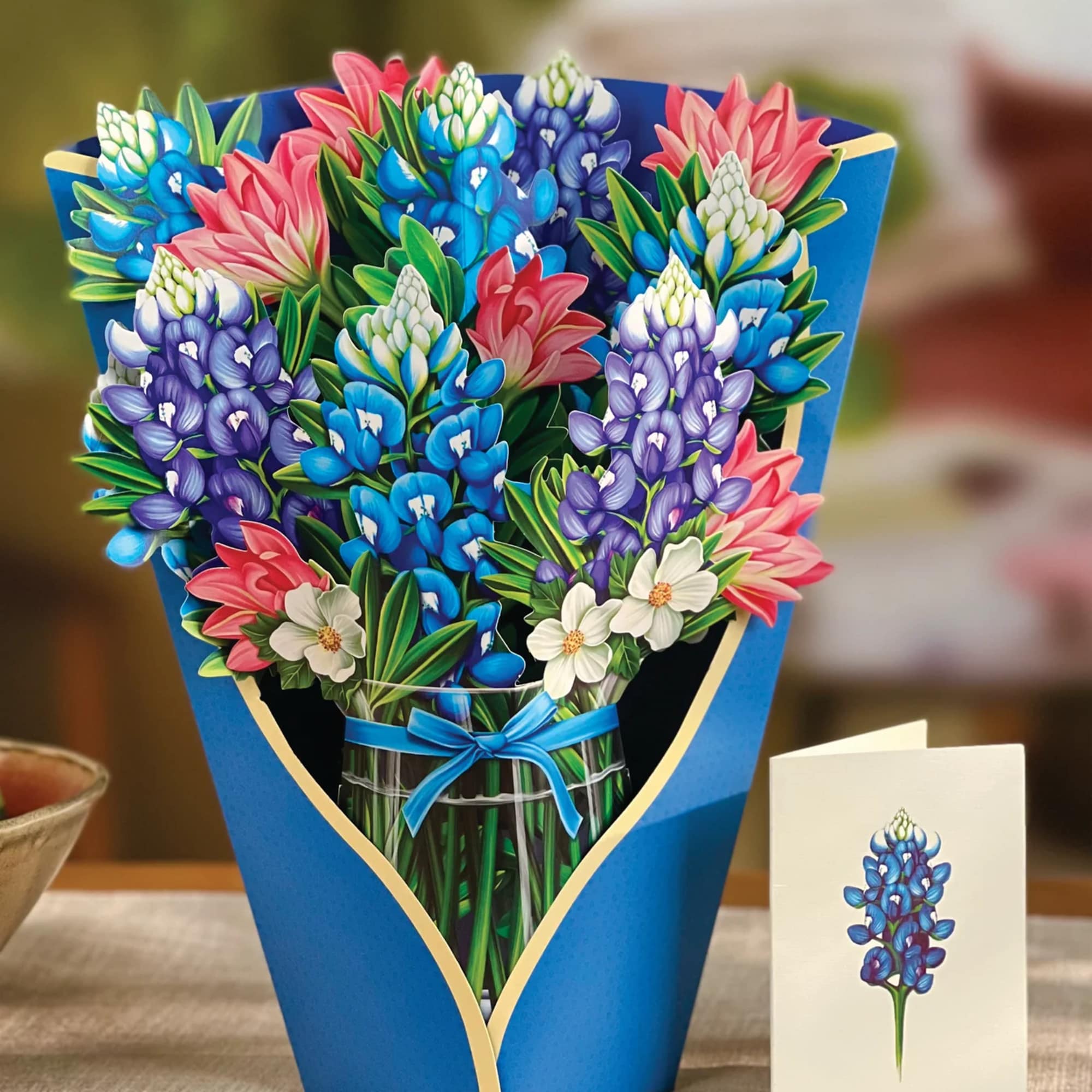 Bouquet of colorful flowers in a blue wrap with a ribbon, beside a matching card