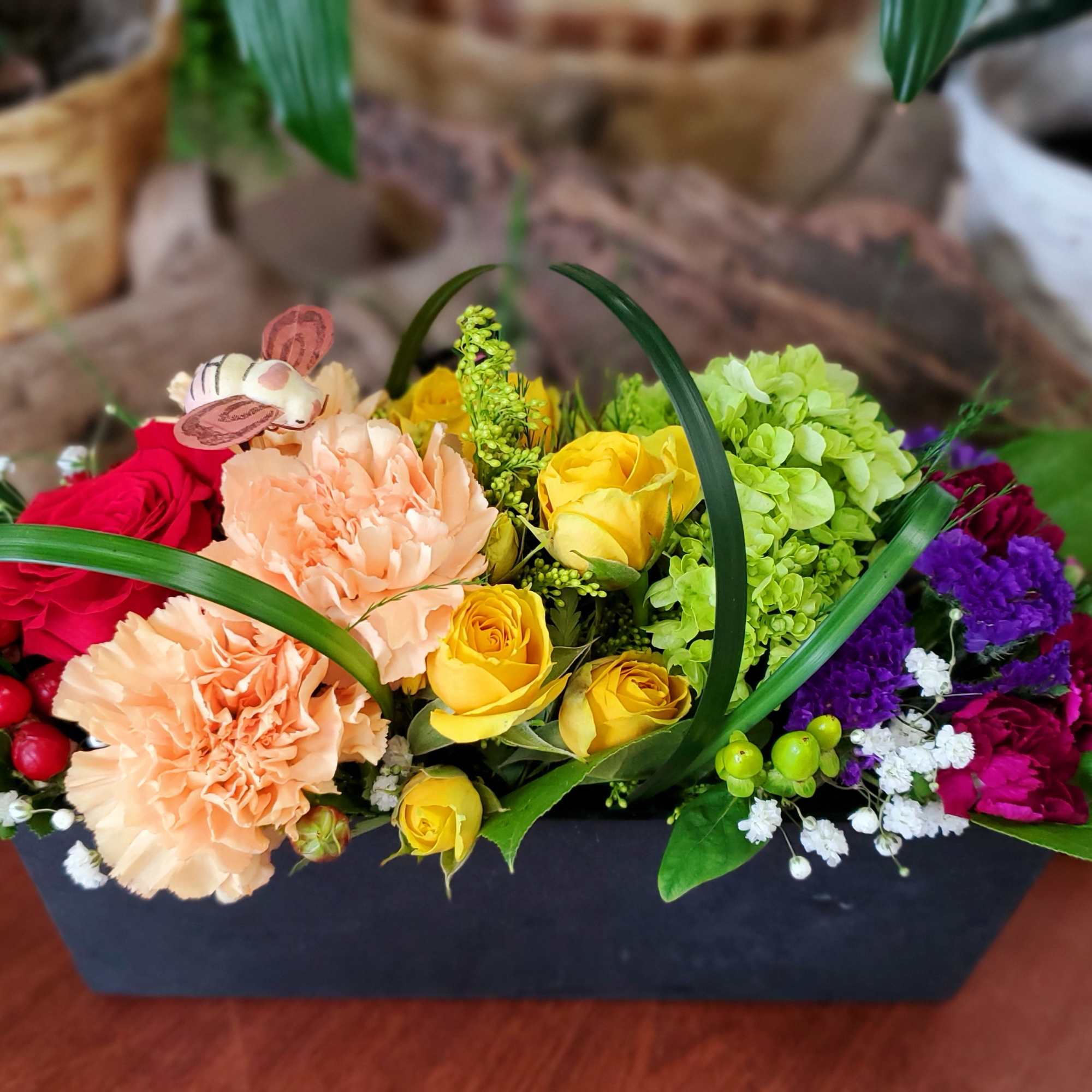 Mixed bouquet in a black rectangular container with roses and carnations