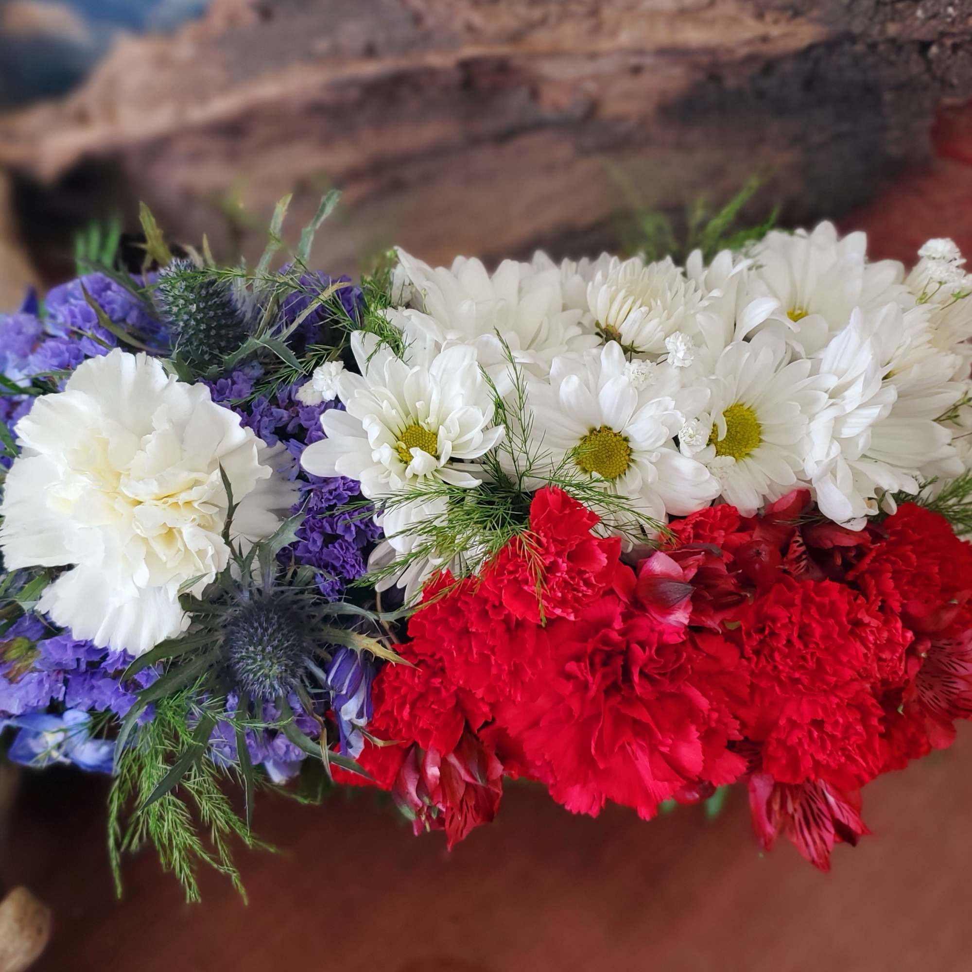 Bouquet of white daisies, red carnations, and purple flowers