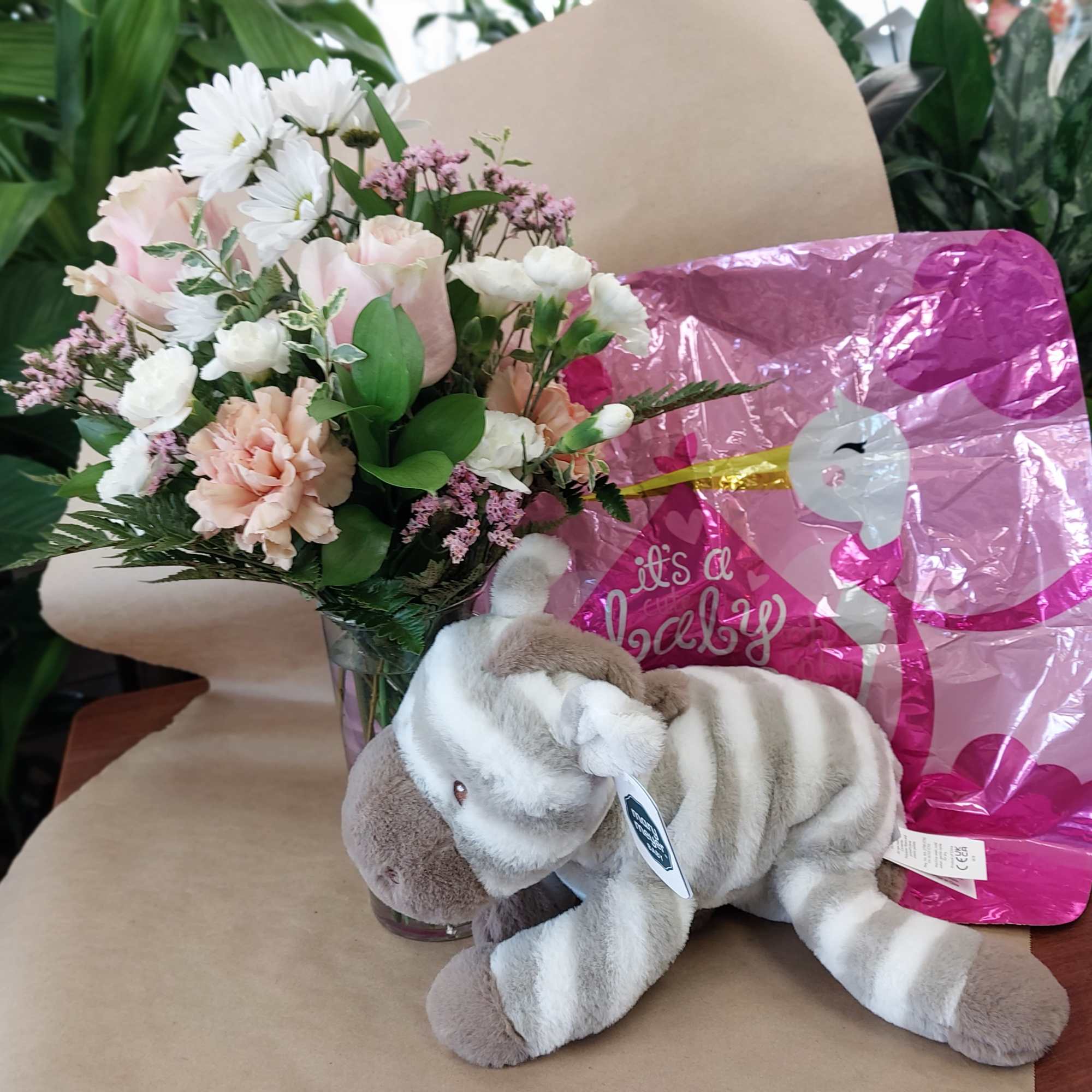 Bouquet of pink and white flowers in a glass vase with a plush zebra toy