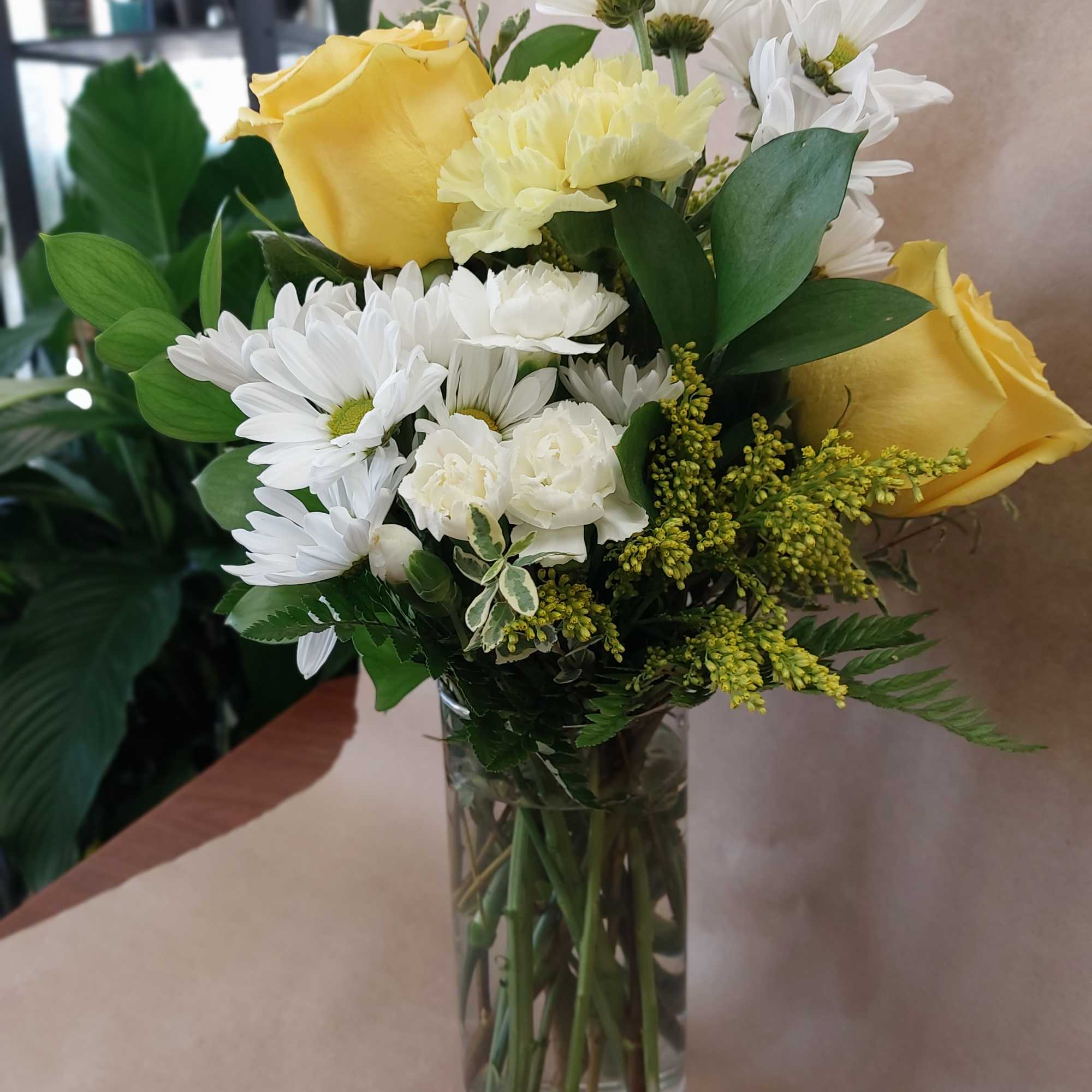 Yellow roses and white daisies in a clear glass vase