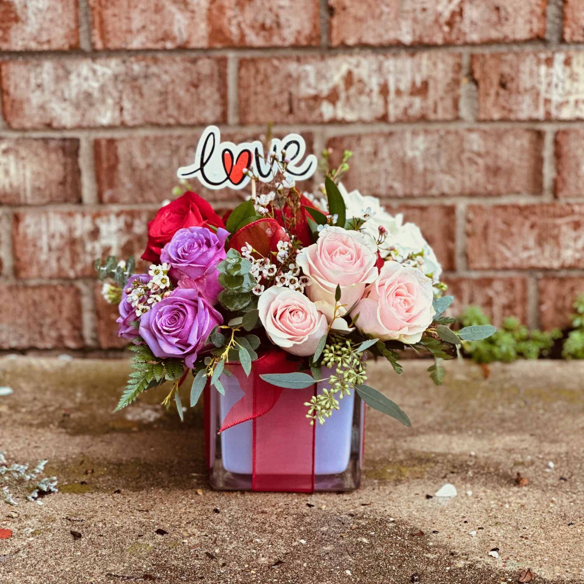 Mixed roses in a square vase with a "love" topper