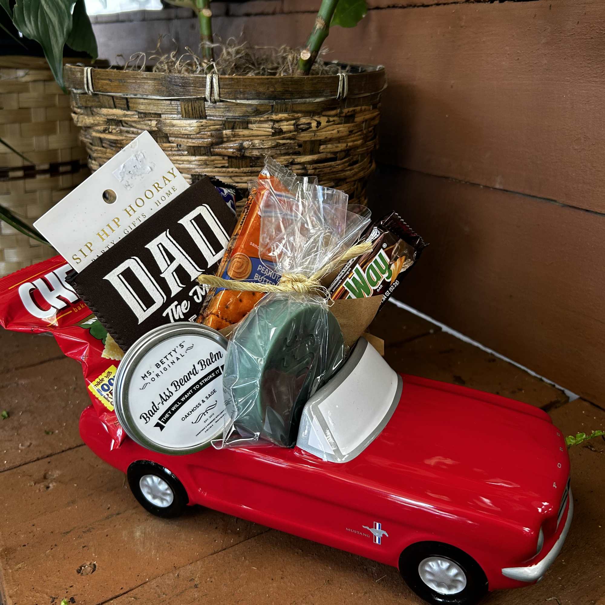 Gift basket arranged in a red toy car with snacks and a candle