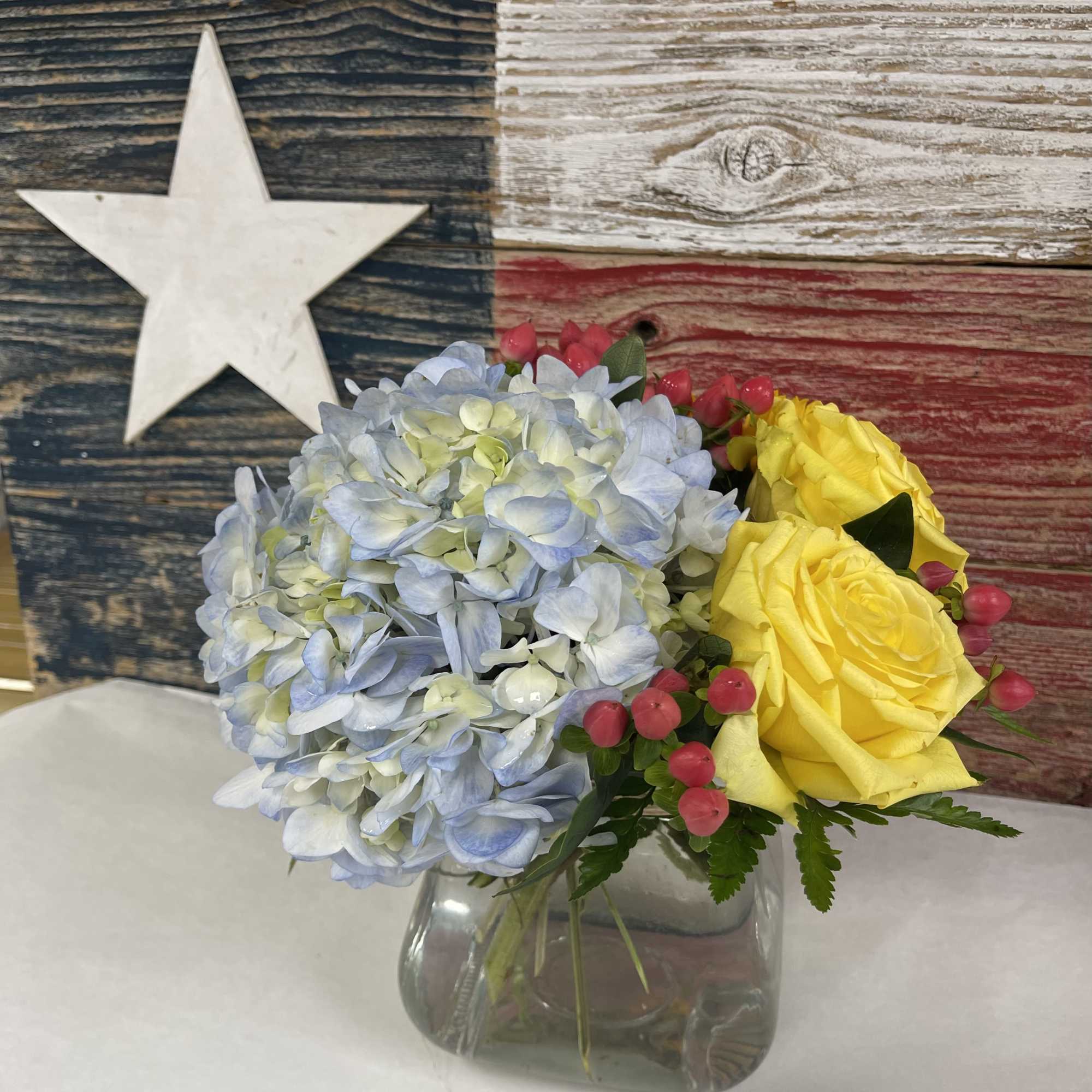Bouquet of blue hydrangea and yellow roses in a clear glass vase