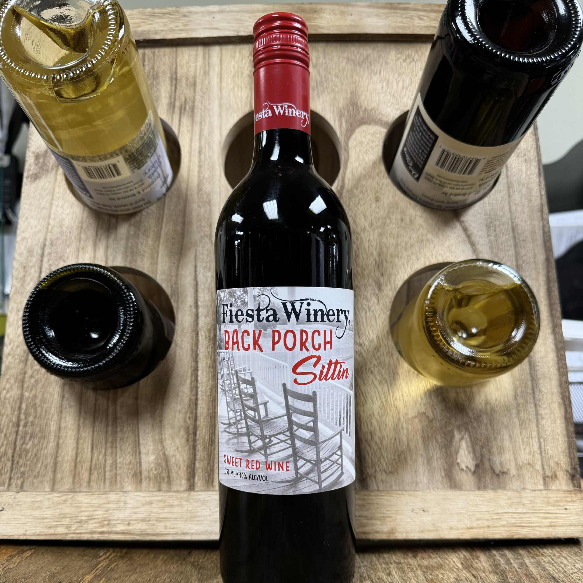 Five wine bottles arranged in a wooden carrier, one labeled Fiesta Winery.